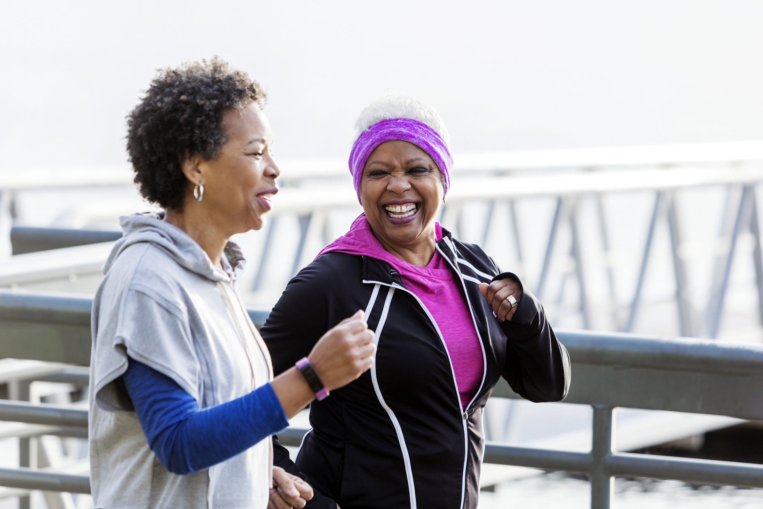two senior woman jogging on a bridge along the water