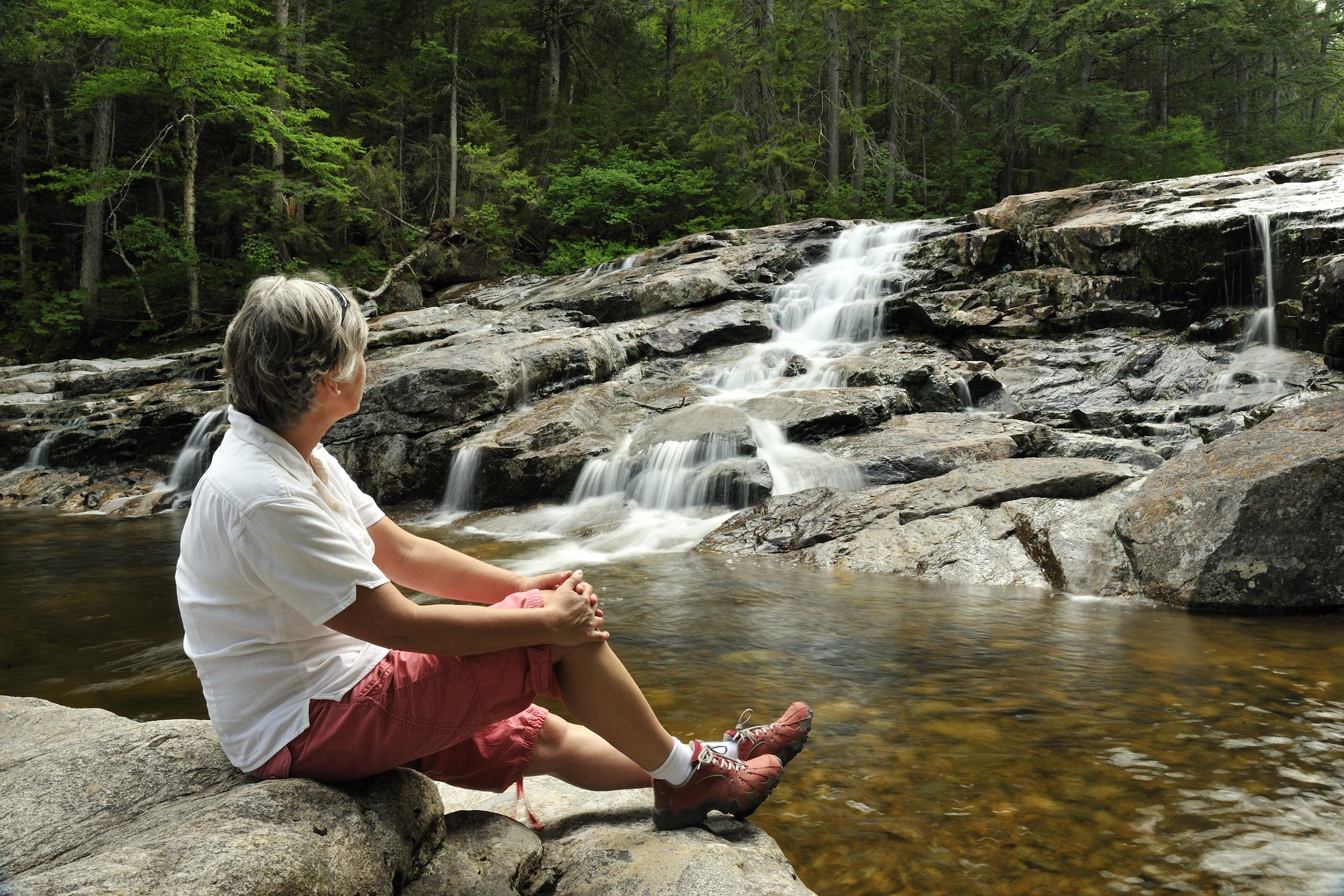 senior woman relaxing near waterfall, Franconia Notch State Park, New Hampshire