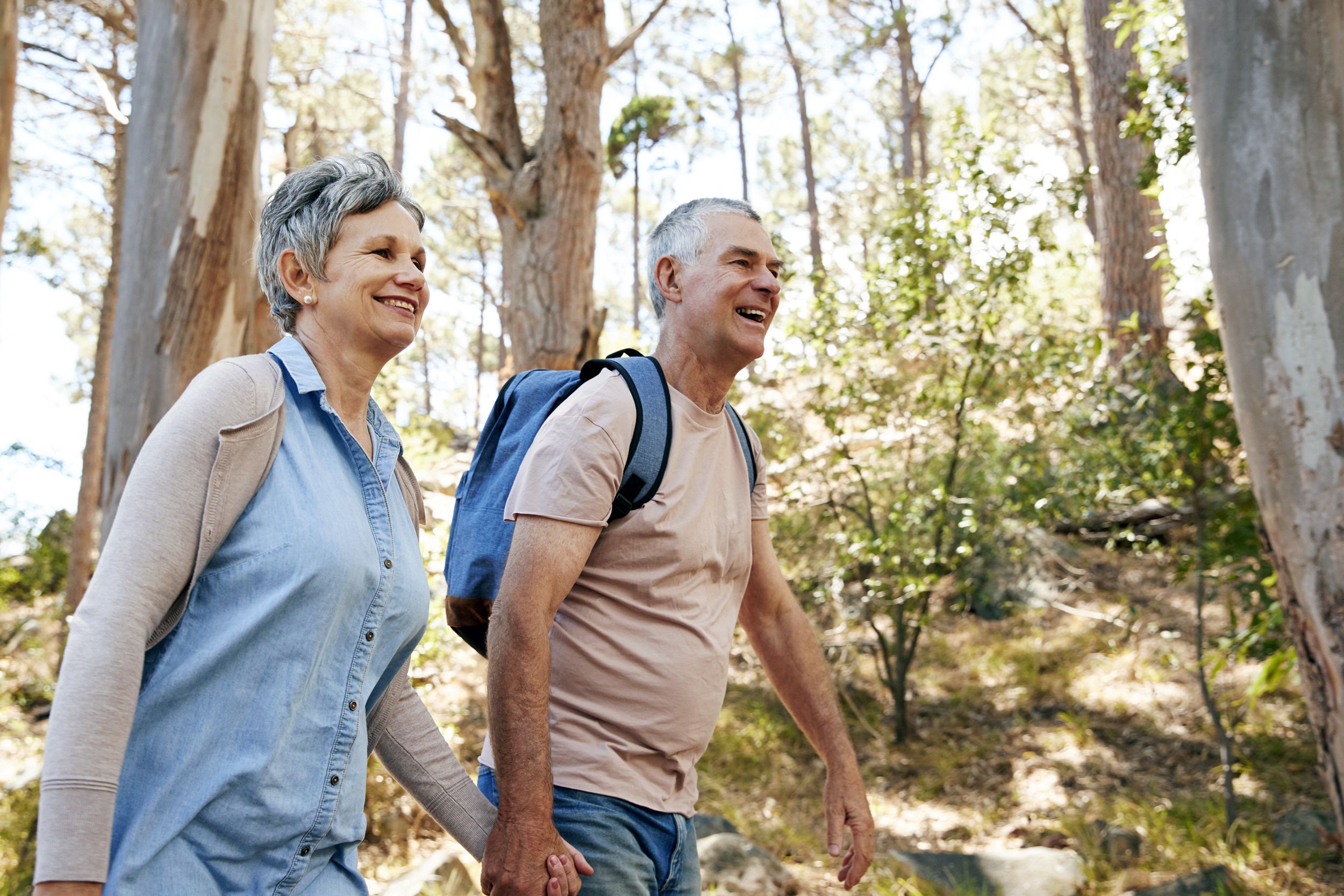 mature couple hiking along forest path together