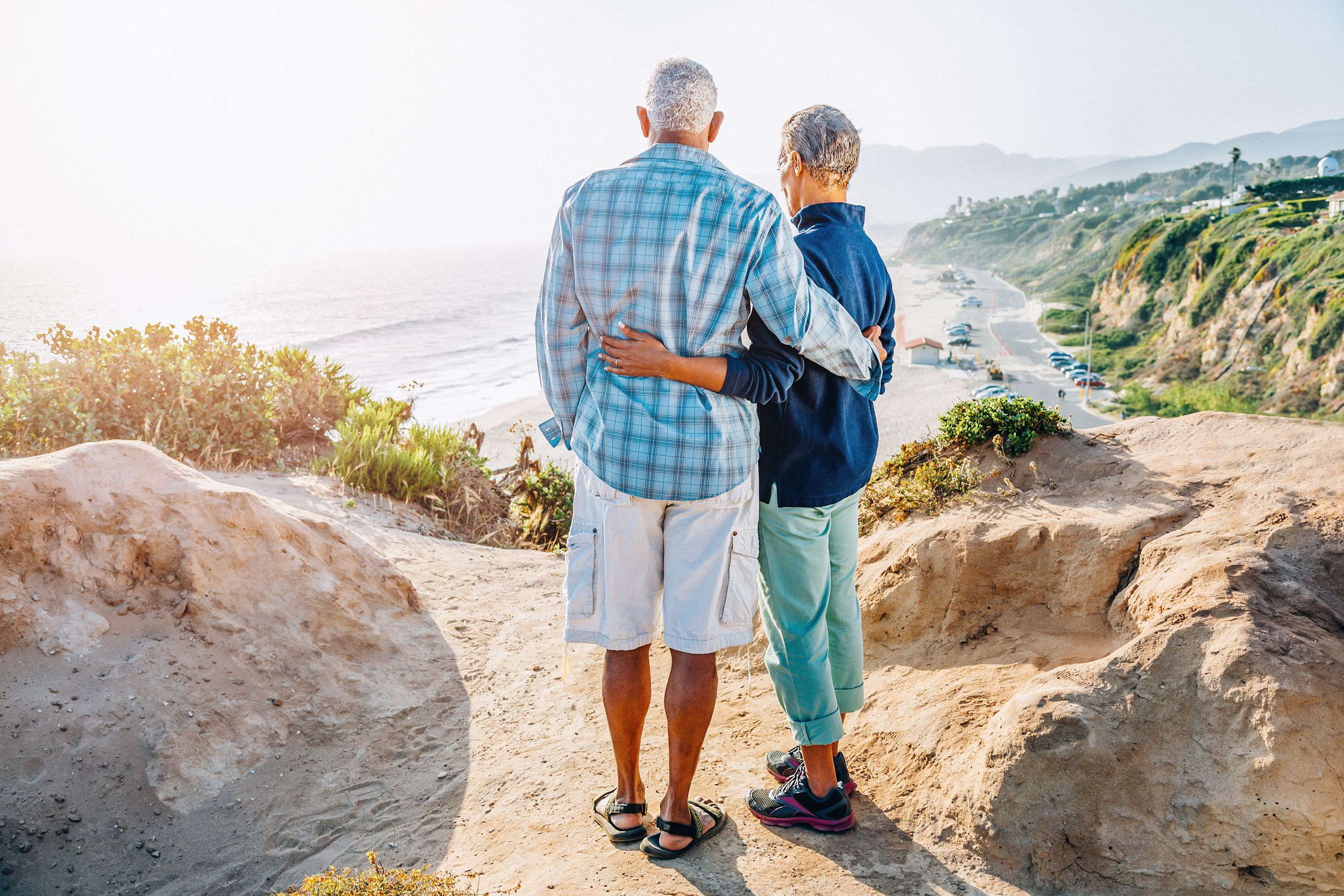 African American senior couple embracing on rock over beach