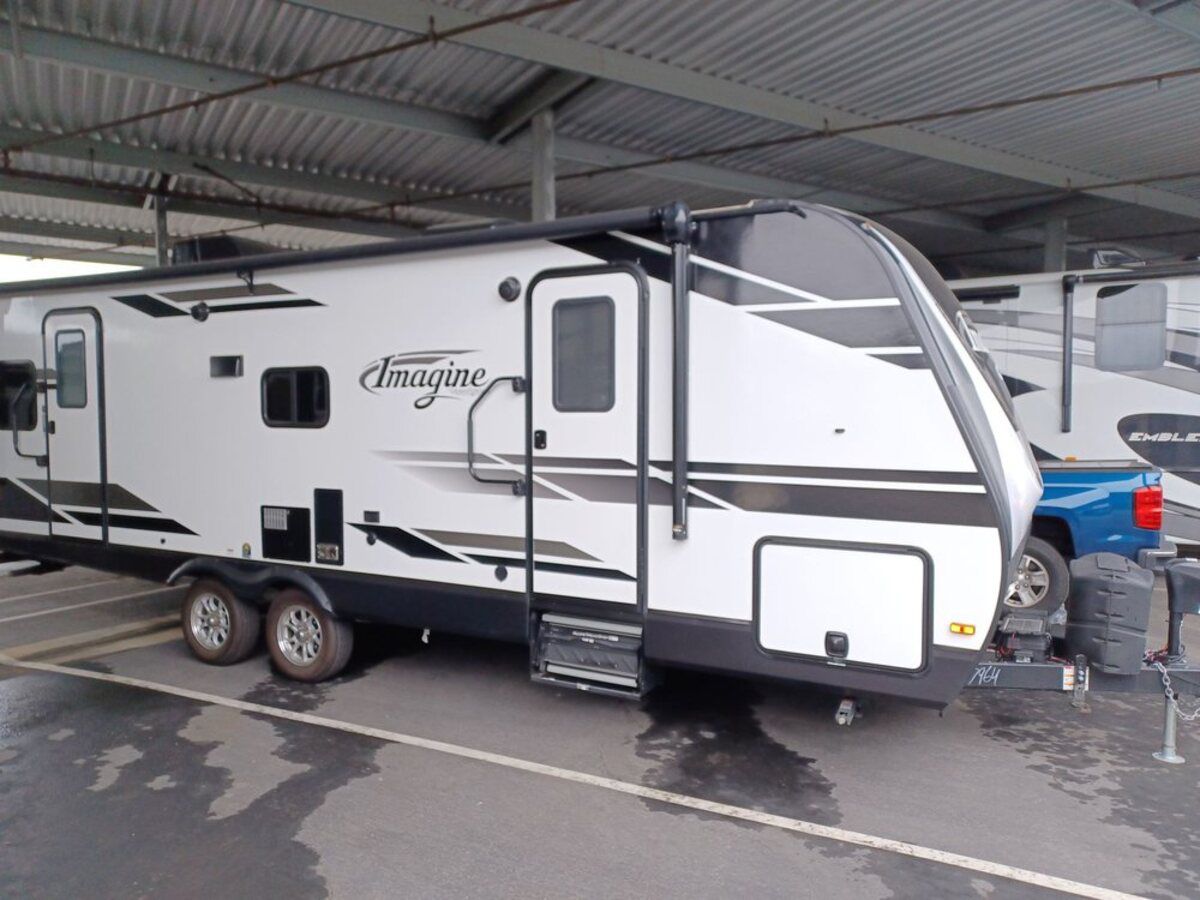 Side-view of an RV for sale at POP RVs, Sarasota, Florida, parked under a shelter
