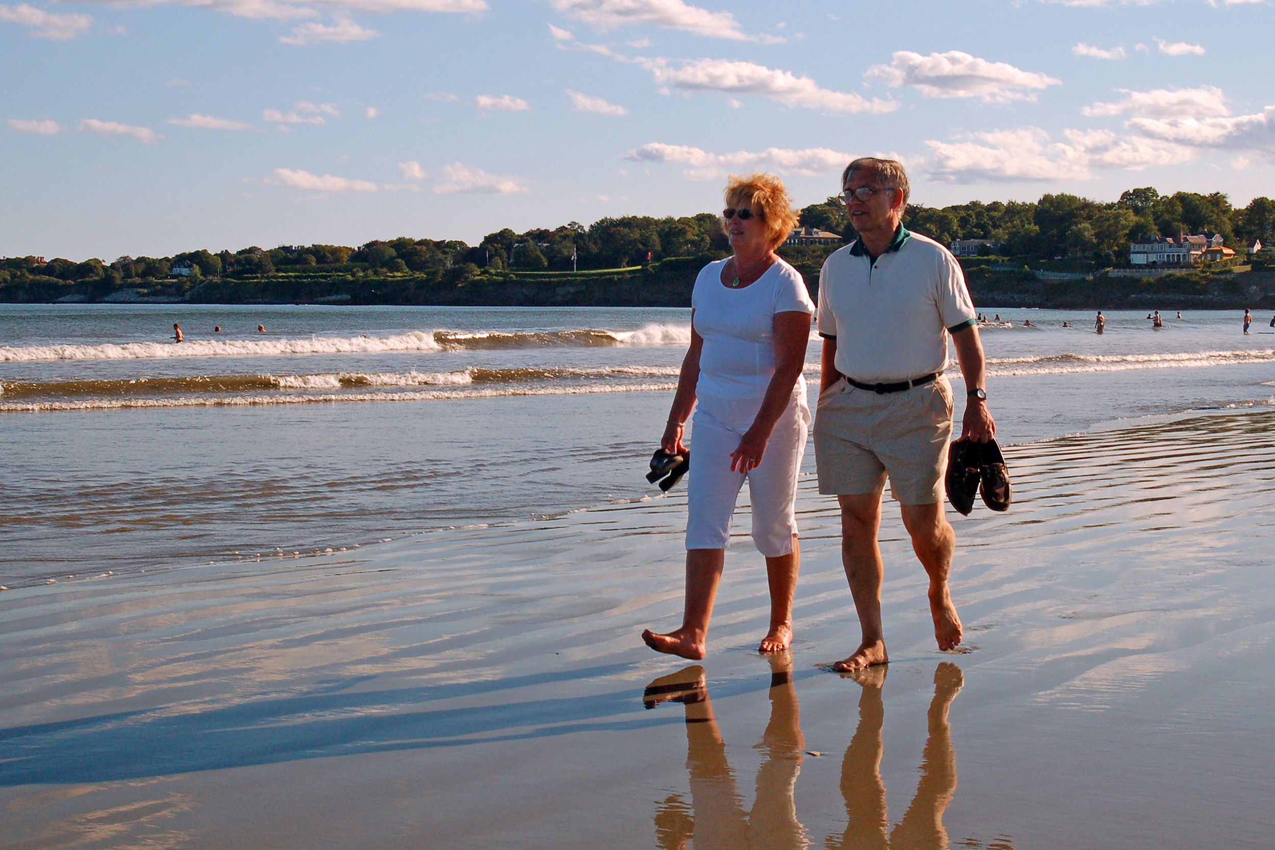 senior couple walk along the beach at Newport, Rhode Island
