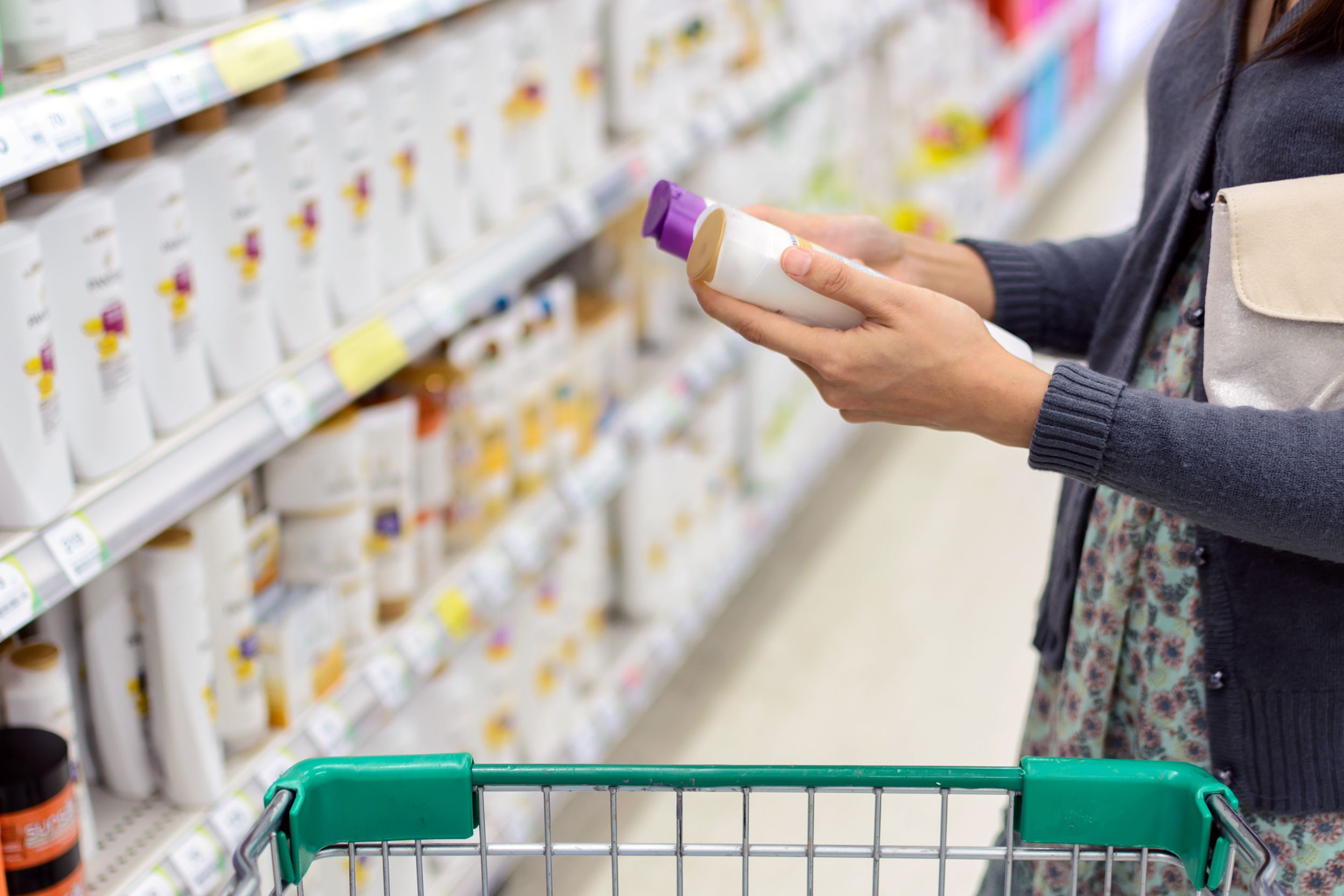women comparing shampoo in supermarket
