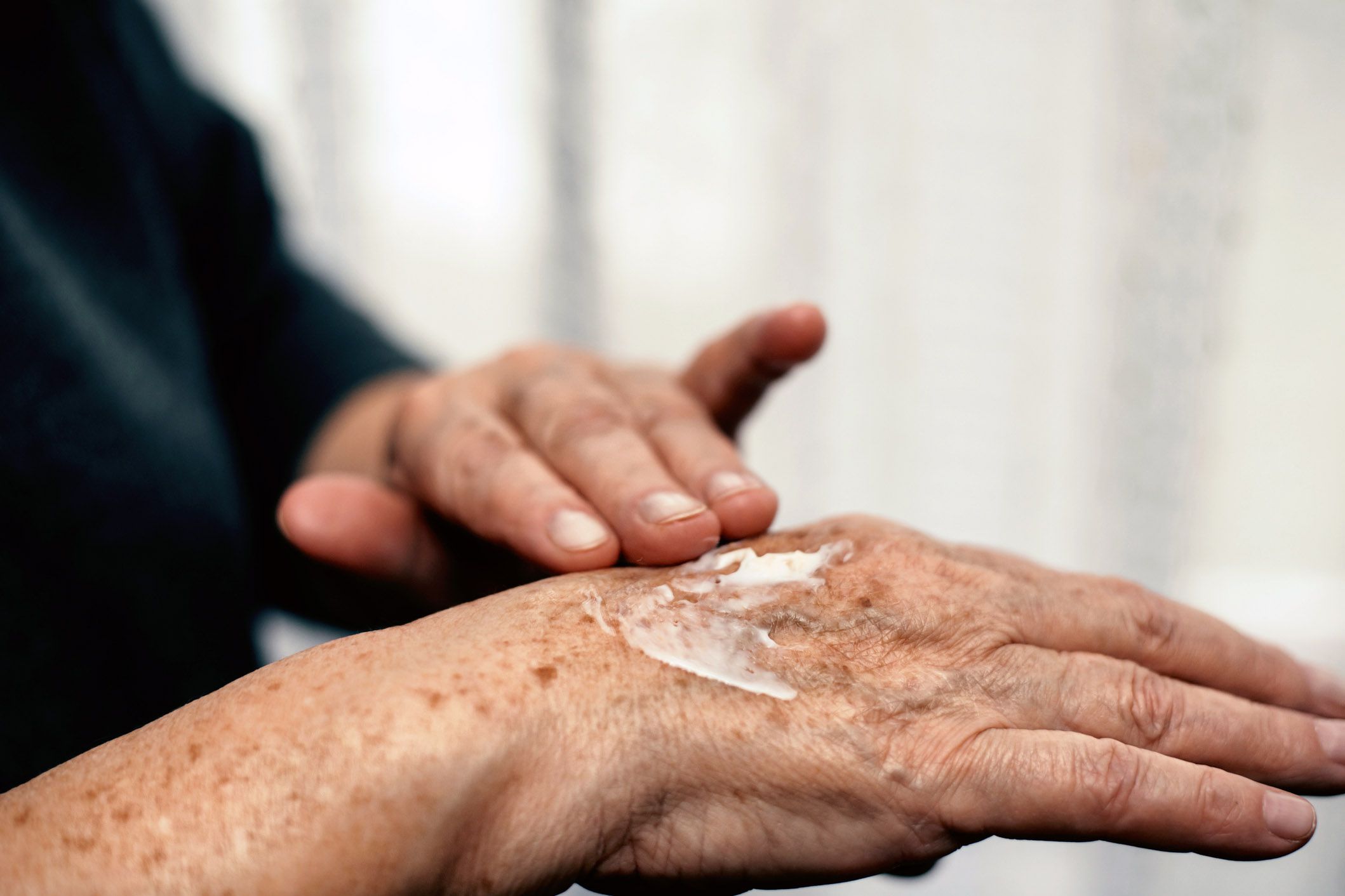 senior hands applying hand cream