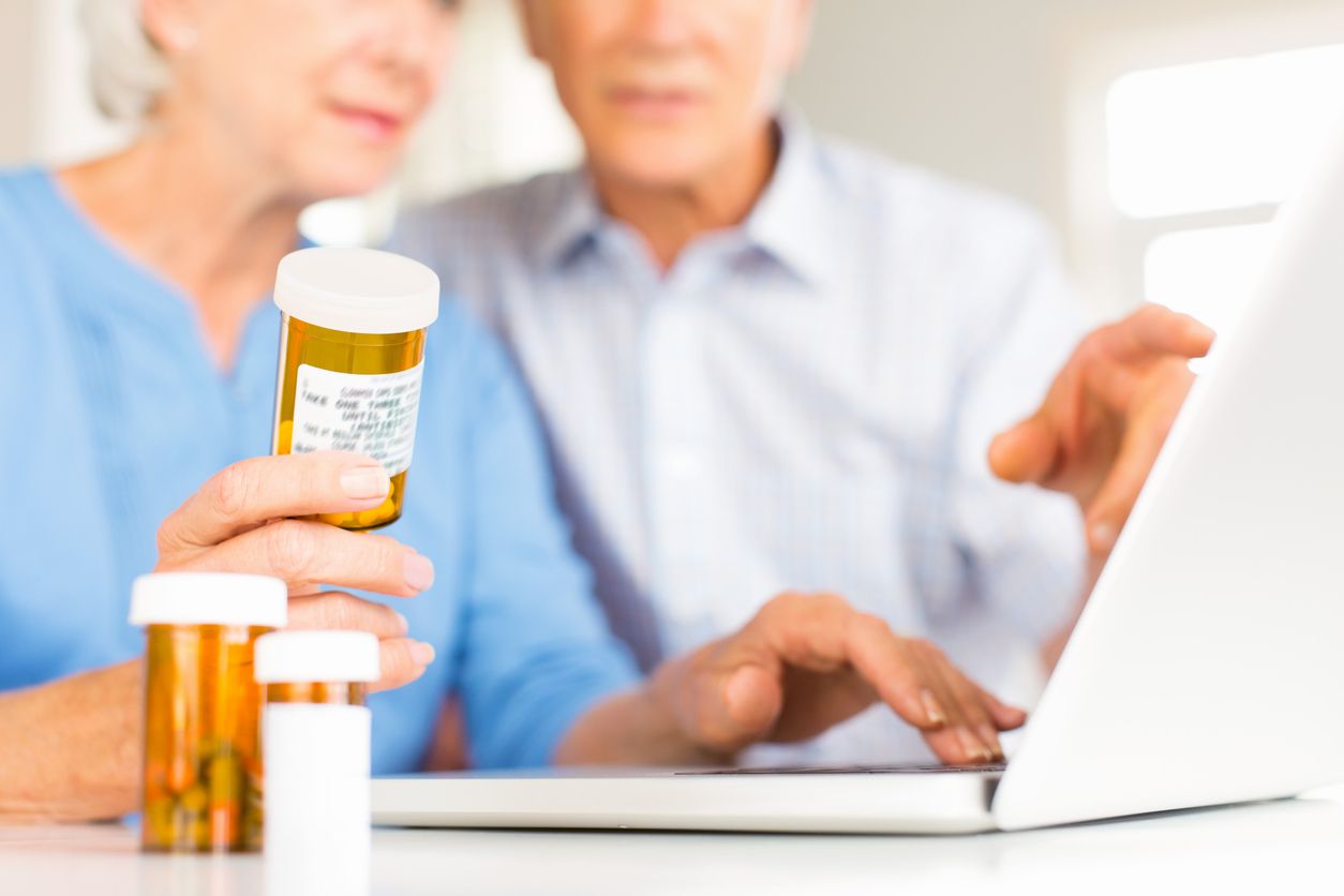 senior on computer with medication