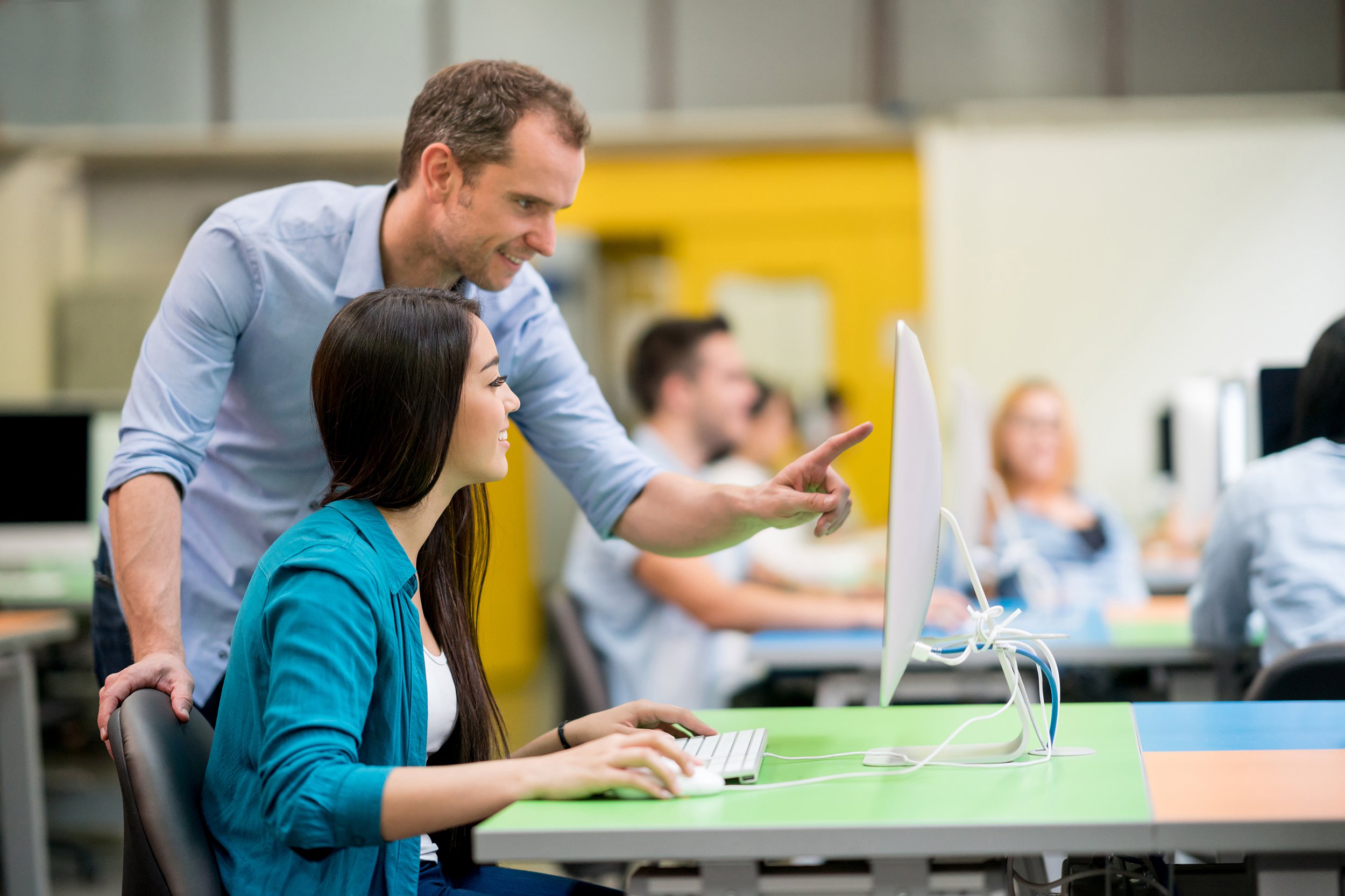 teacher helping student at an IT class