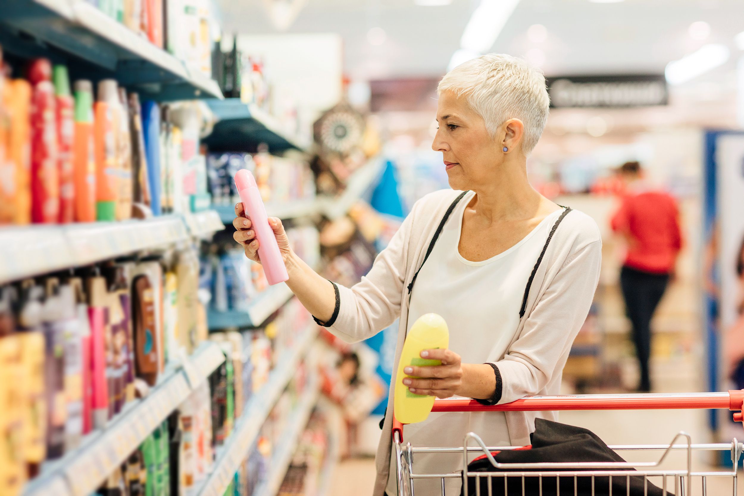 senior woman shopping for shampoo in grocery store