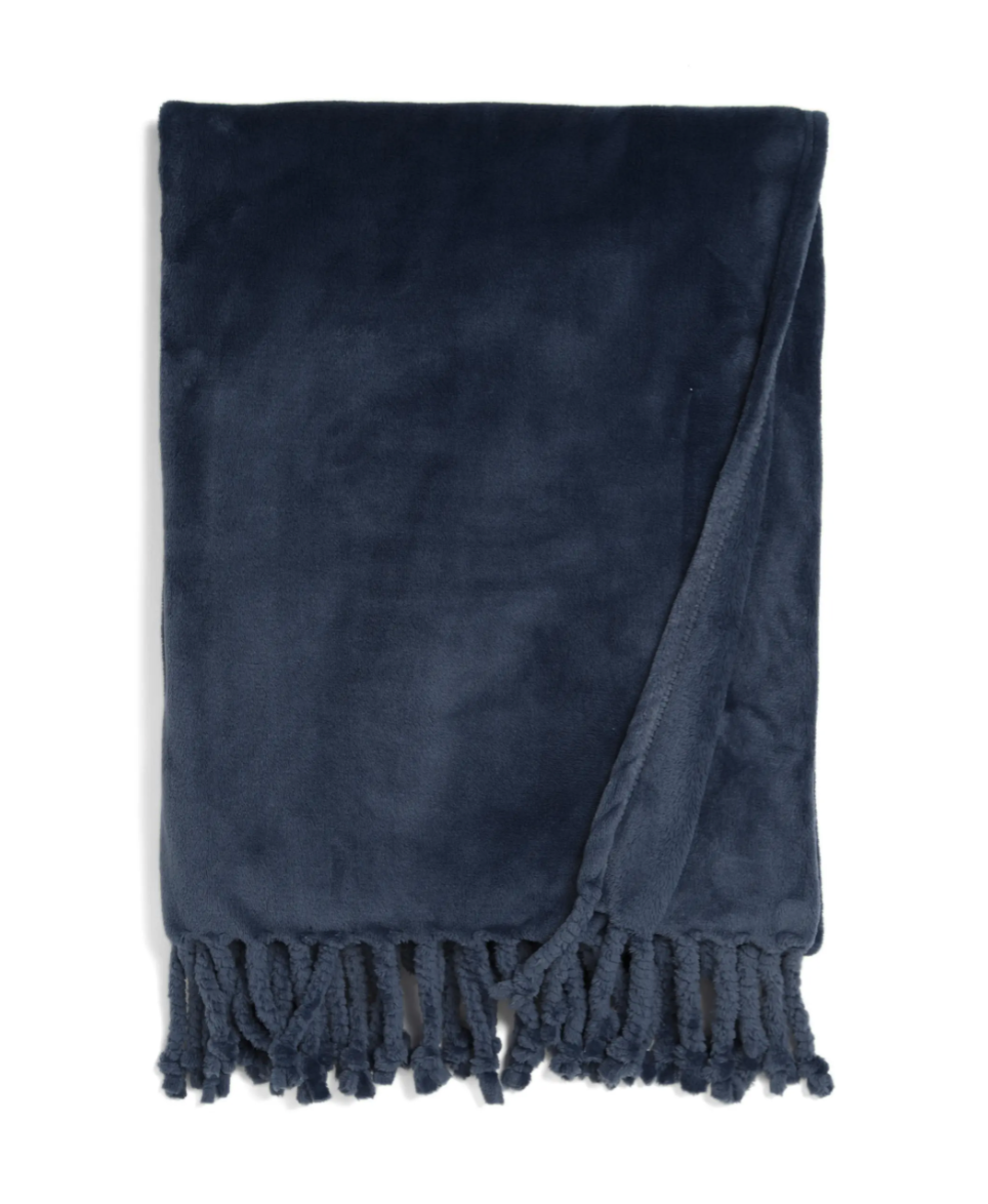 A folded dark blue fleece blanket with fringed tassels along the bottom edge, displayed on a white background.