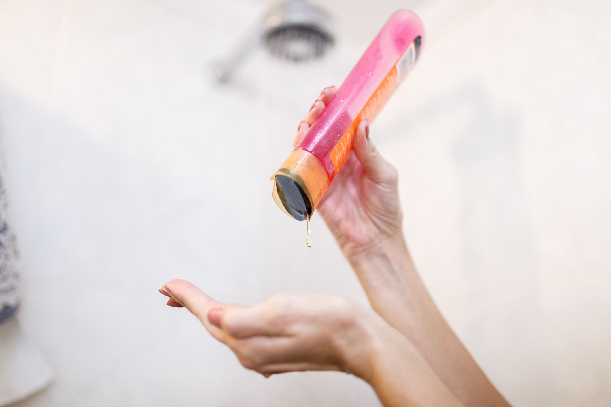 female hands pouring shampoo from bottle