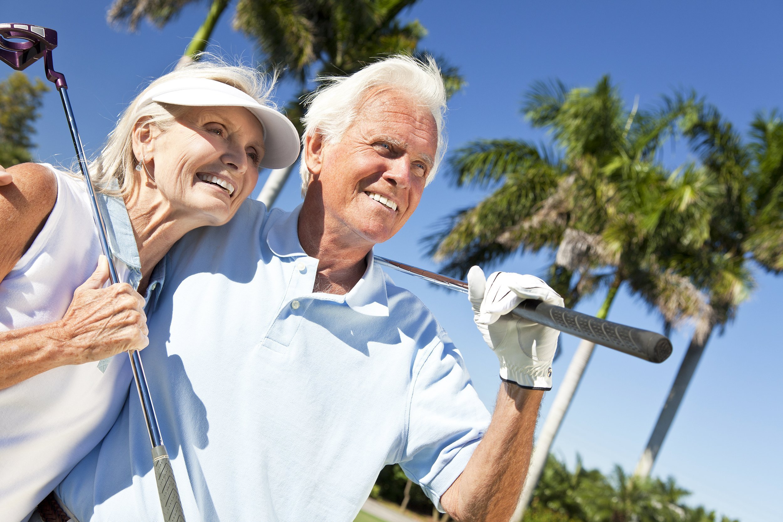 happy senior couple together playing golf putting on a green together
