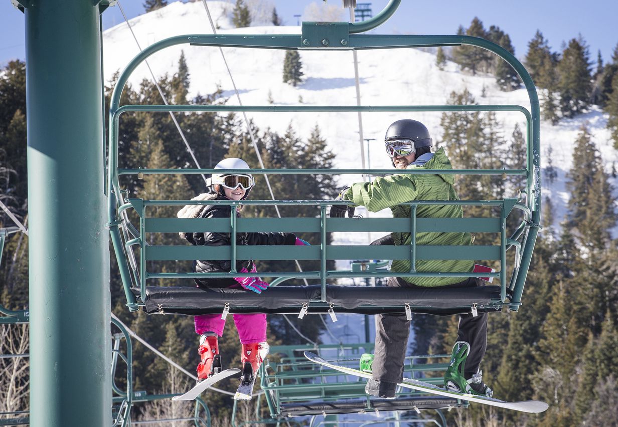 father and daughter riding a chair lift