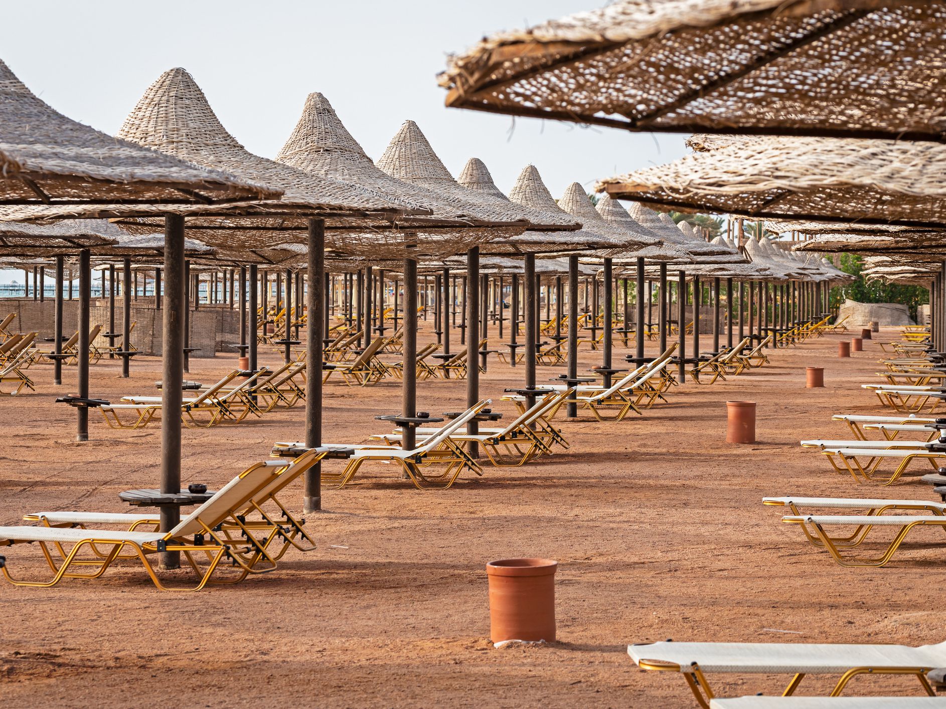 Empty Egyptian beach with wooden umbrellas and sun beds during the outbreak of the Covid 19 virus. Concept of the spread of coronavirus and the crisis of the tourism industry.