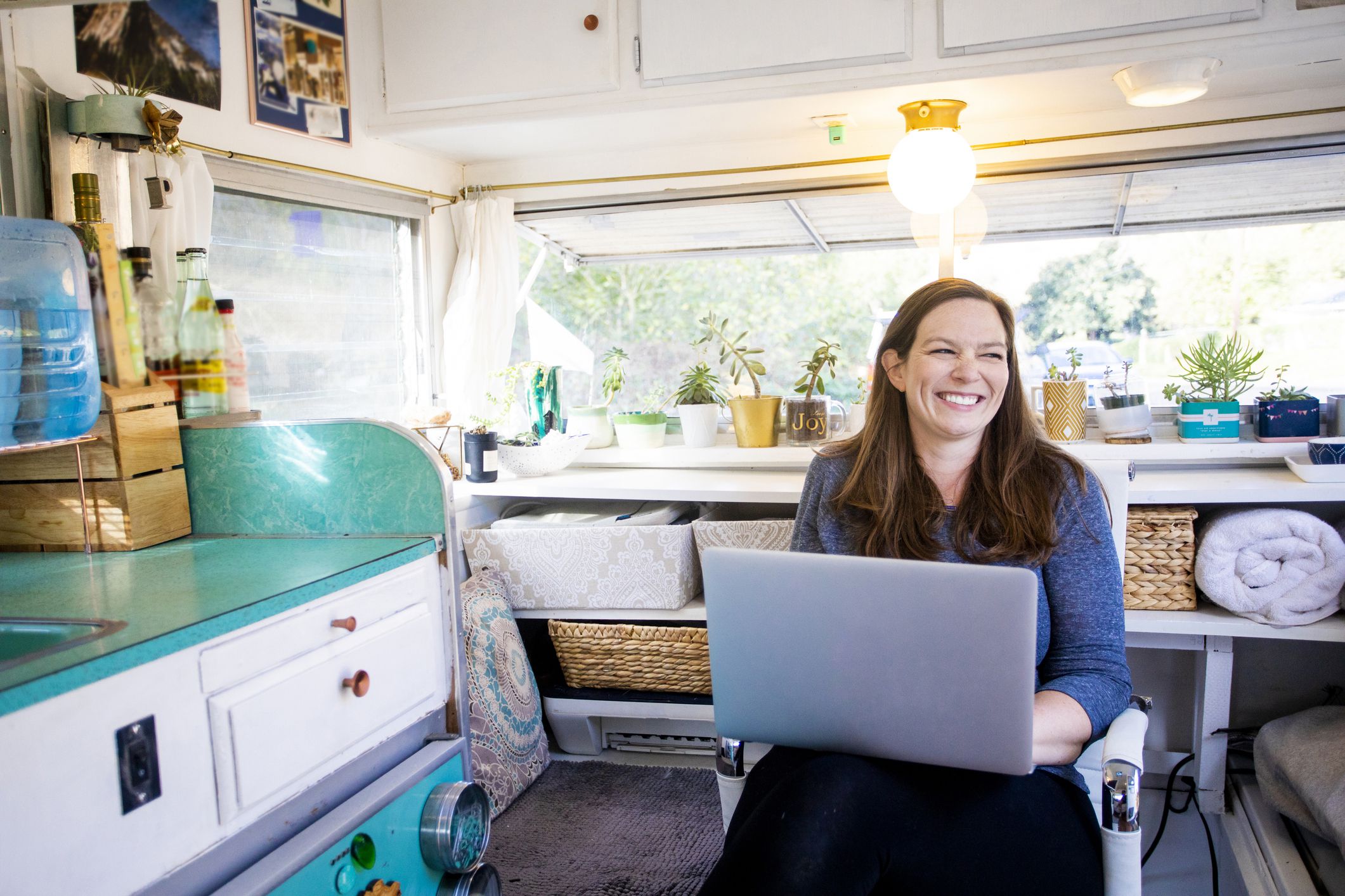A young woman setting up camp in the wilderness with her trailer