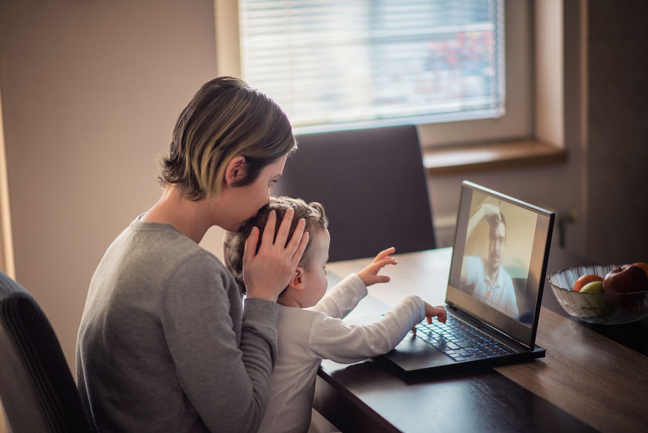 Mother and baby boy, toddler, talking with father on a Skype, using laptop, having family moment during video call, adjusting to separation during coronavirus, covid 19 quarantine.