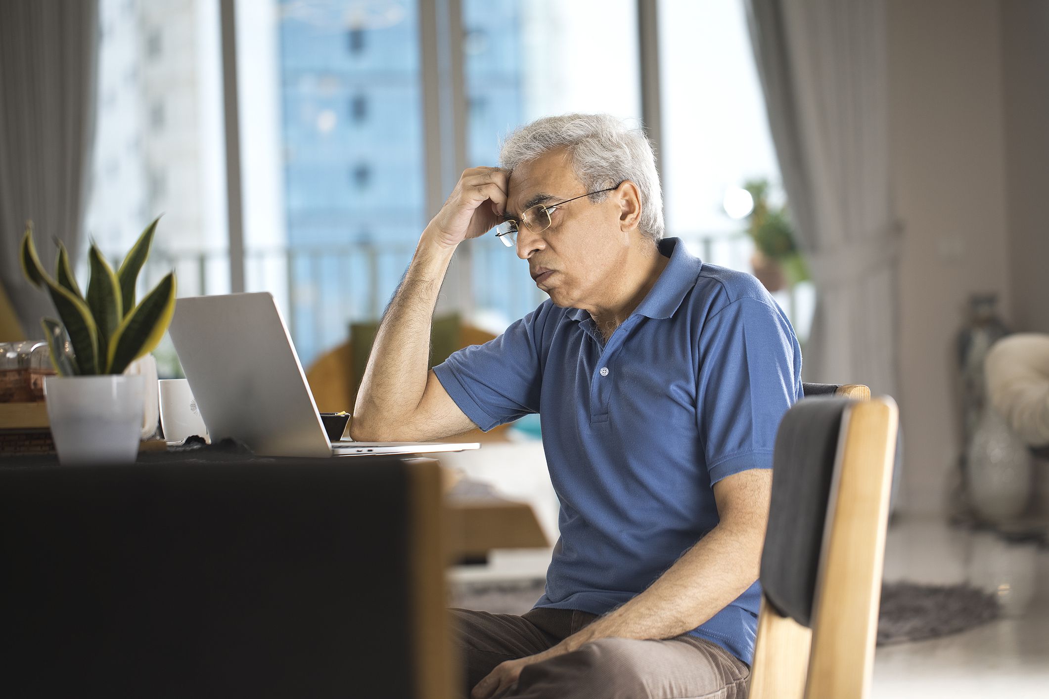 Displeased senior man using laptop at home