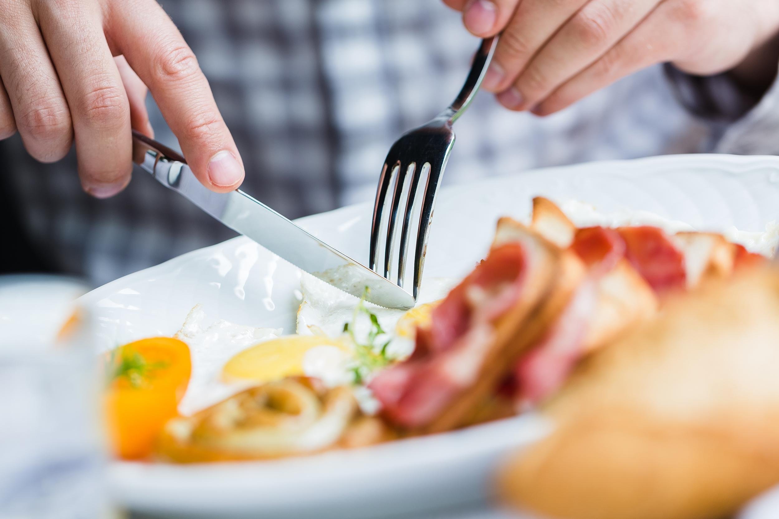 man eating breakfast of eggs, bacon