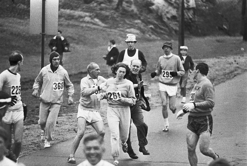 Trainer Jock Semple -- in street clothes -- enters the field of runners (left) to try to pull Kathy Switzer (261) out of the race.