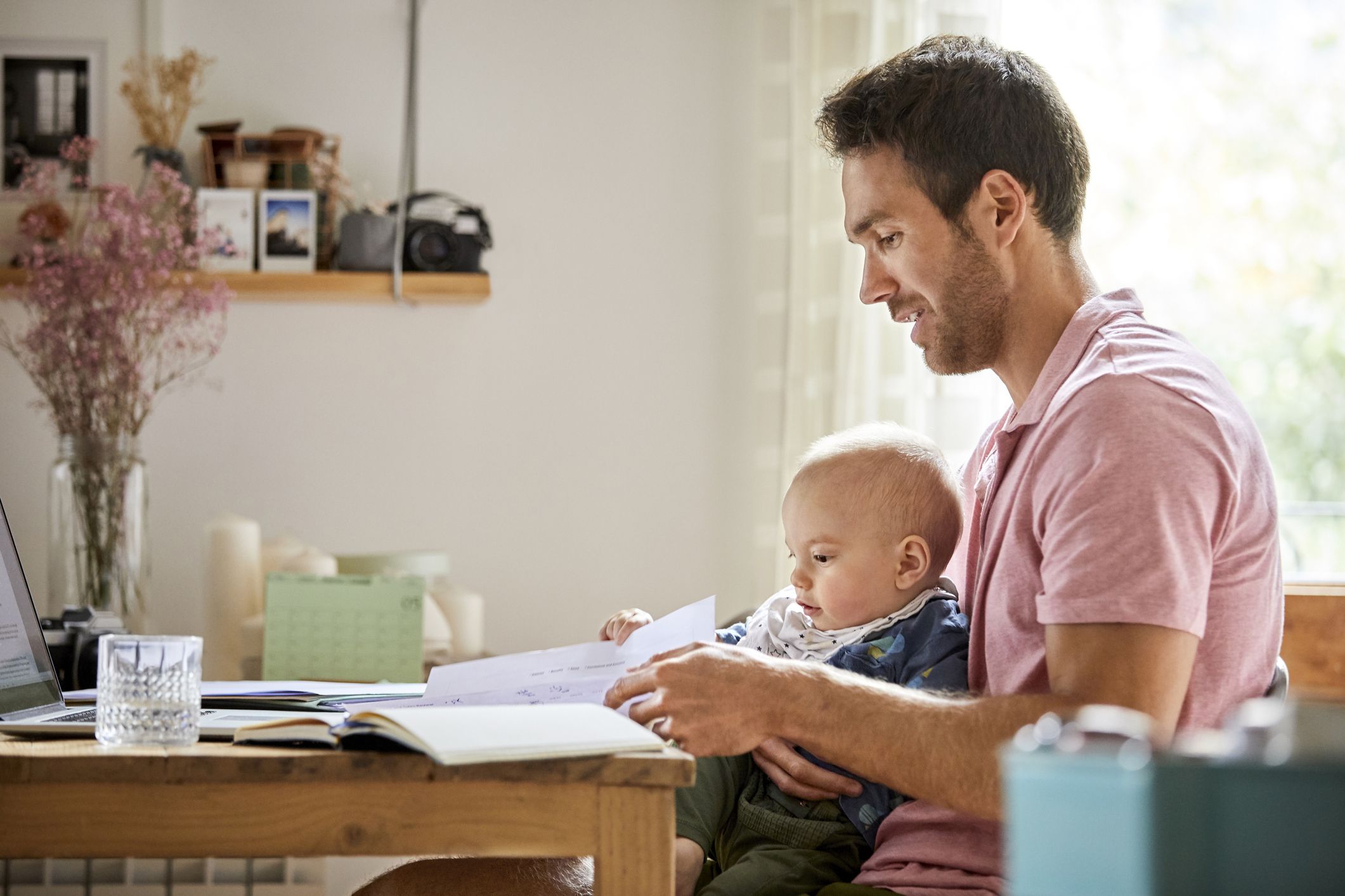 Mid adult father analyzing documents while sitting with baby boy