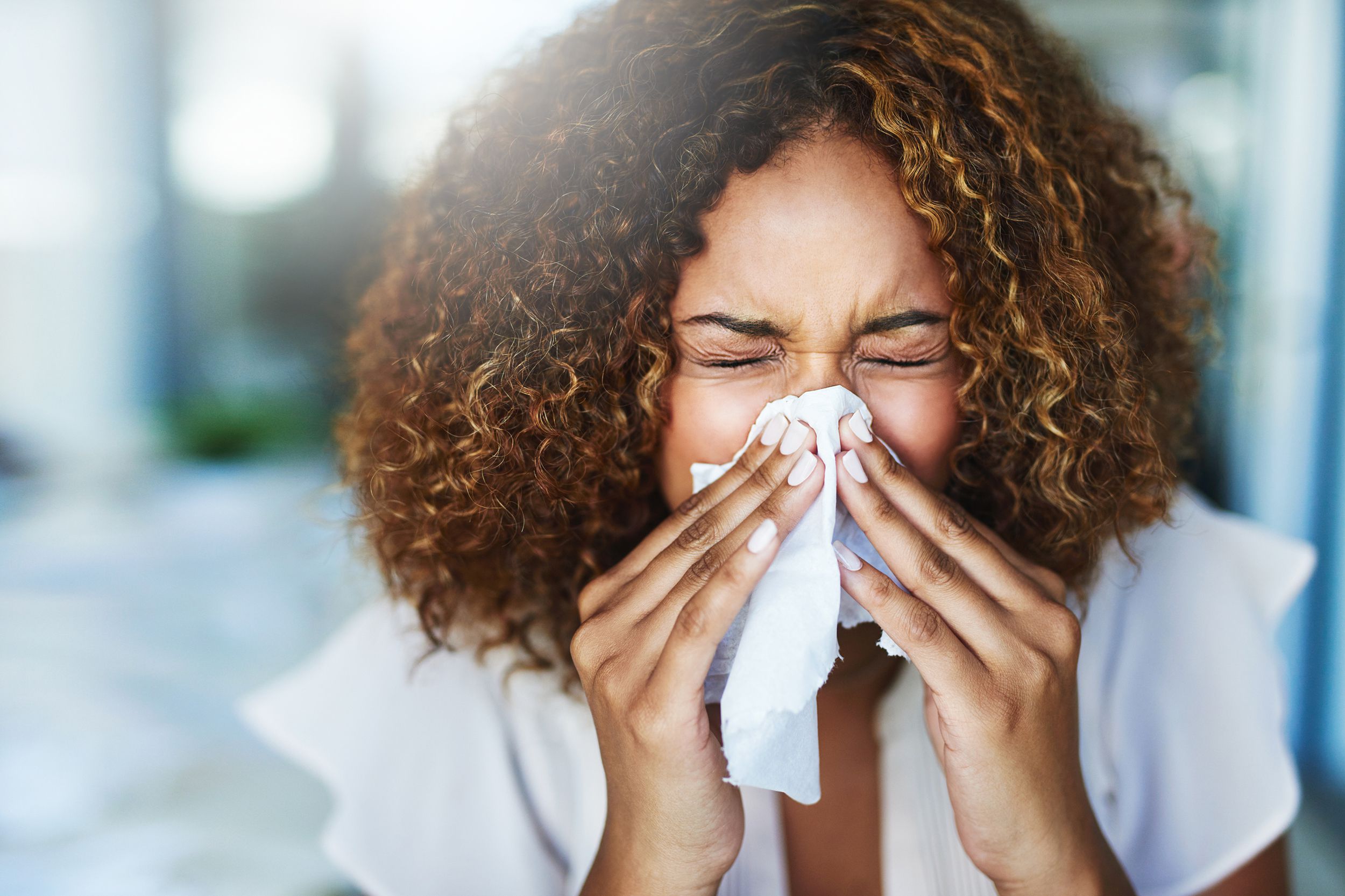 woman sneezing from allergies in the office