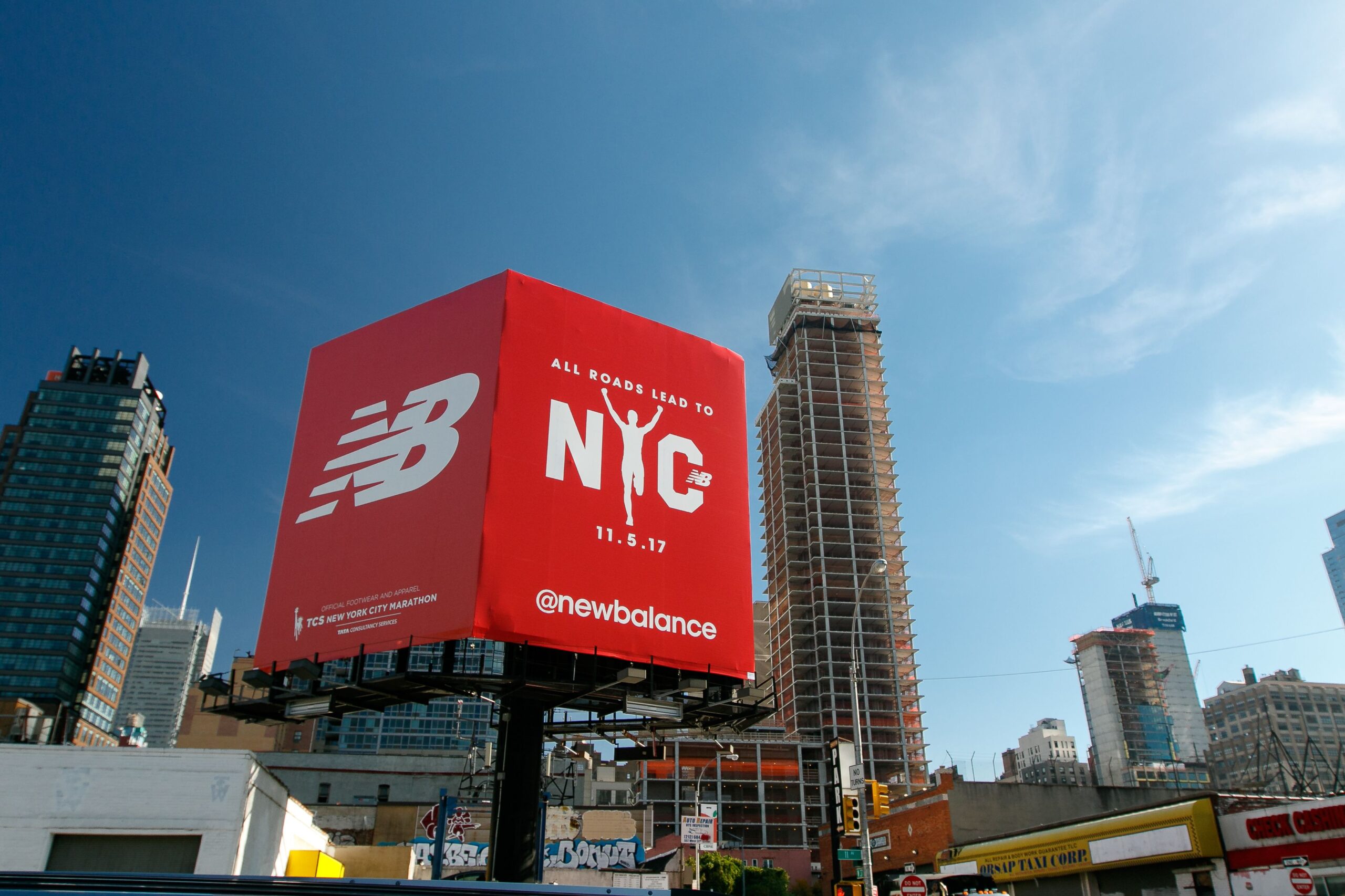 Big red billboard for New Balance sports footwear manufacturer that also announces the NYC marathon.