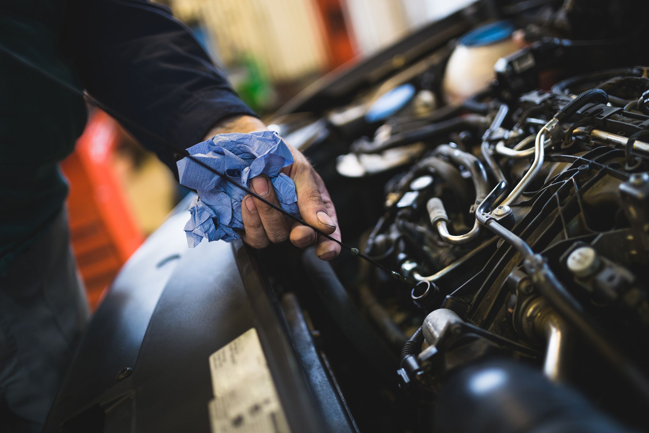 mechanic worker hands close up checking oil of car