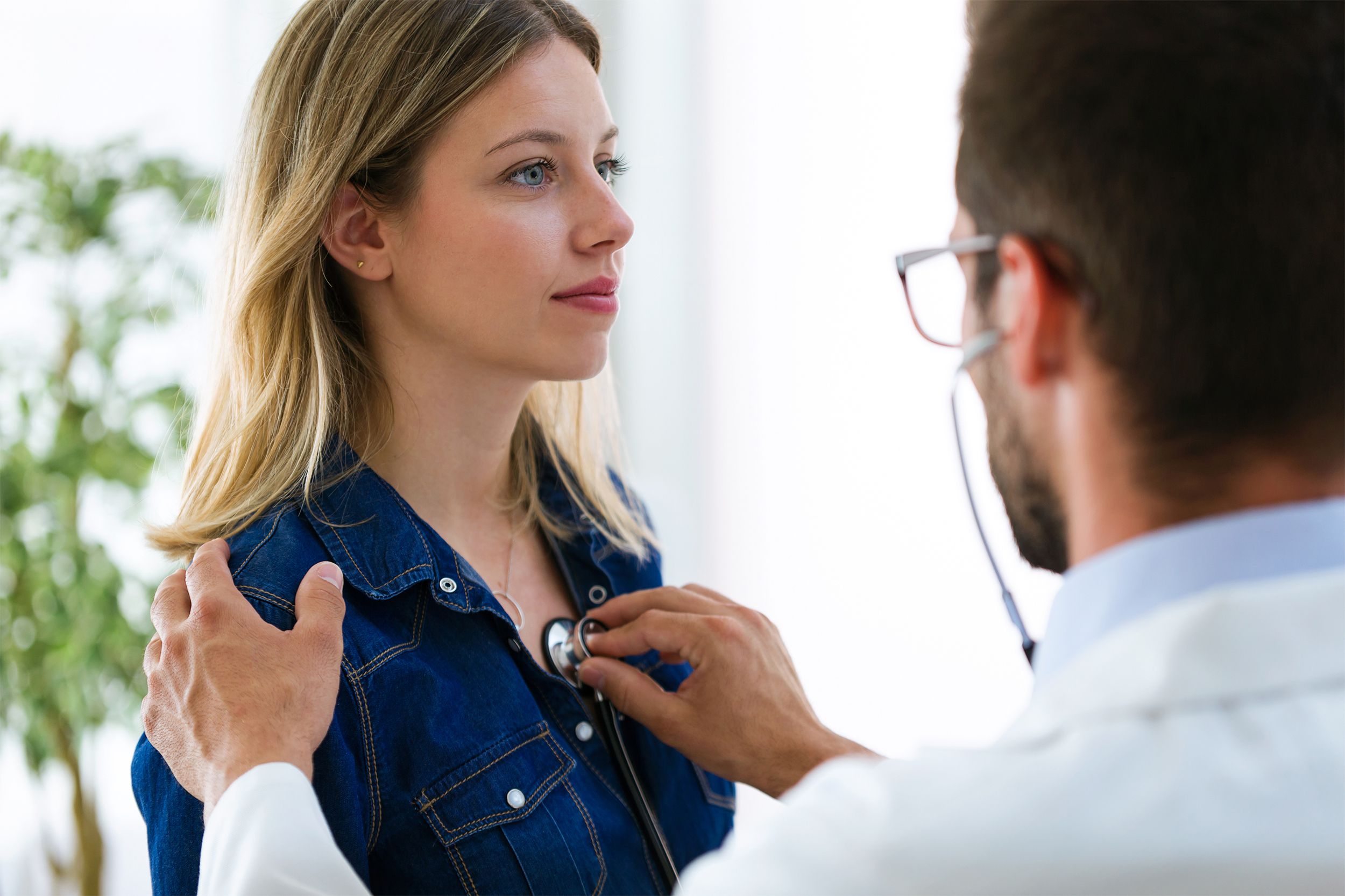 Doctor checking heartbeat of young female patient