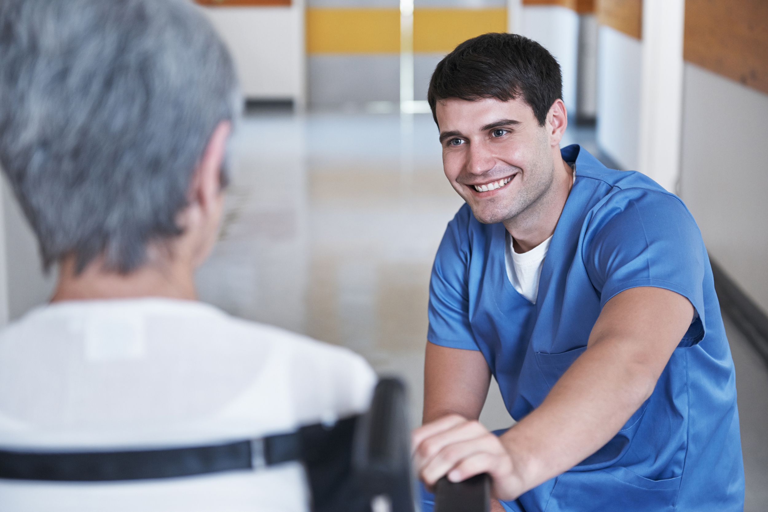 man smiling at senior patient in wheelchair