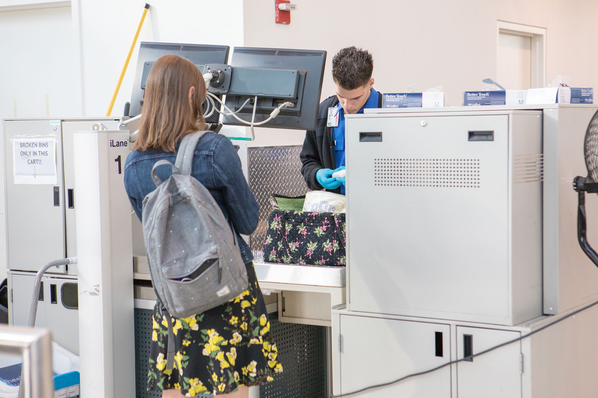 female airline passenger having bag searched by TSA