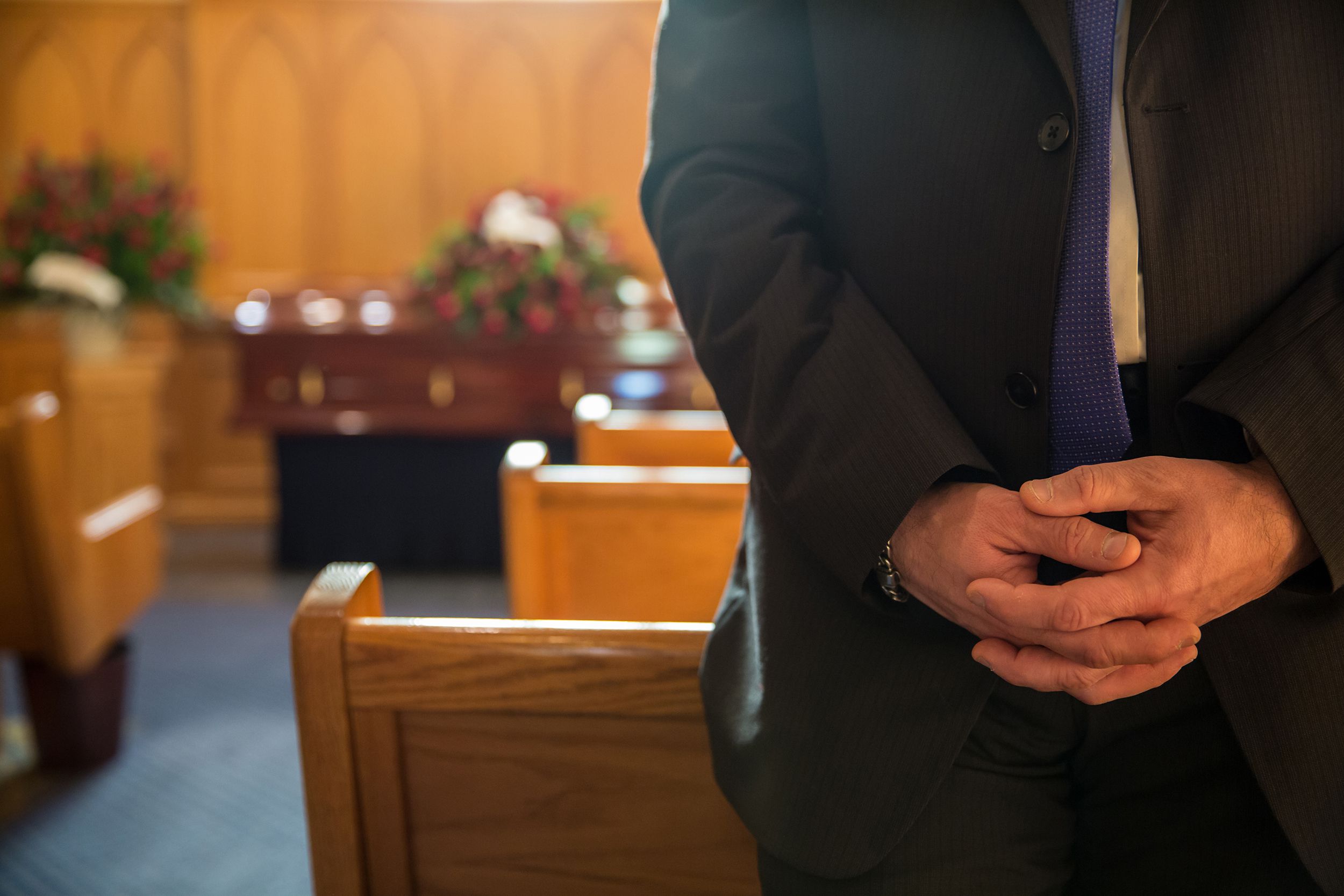 funeral attendant standing with hands folded