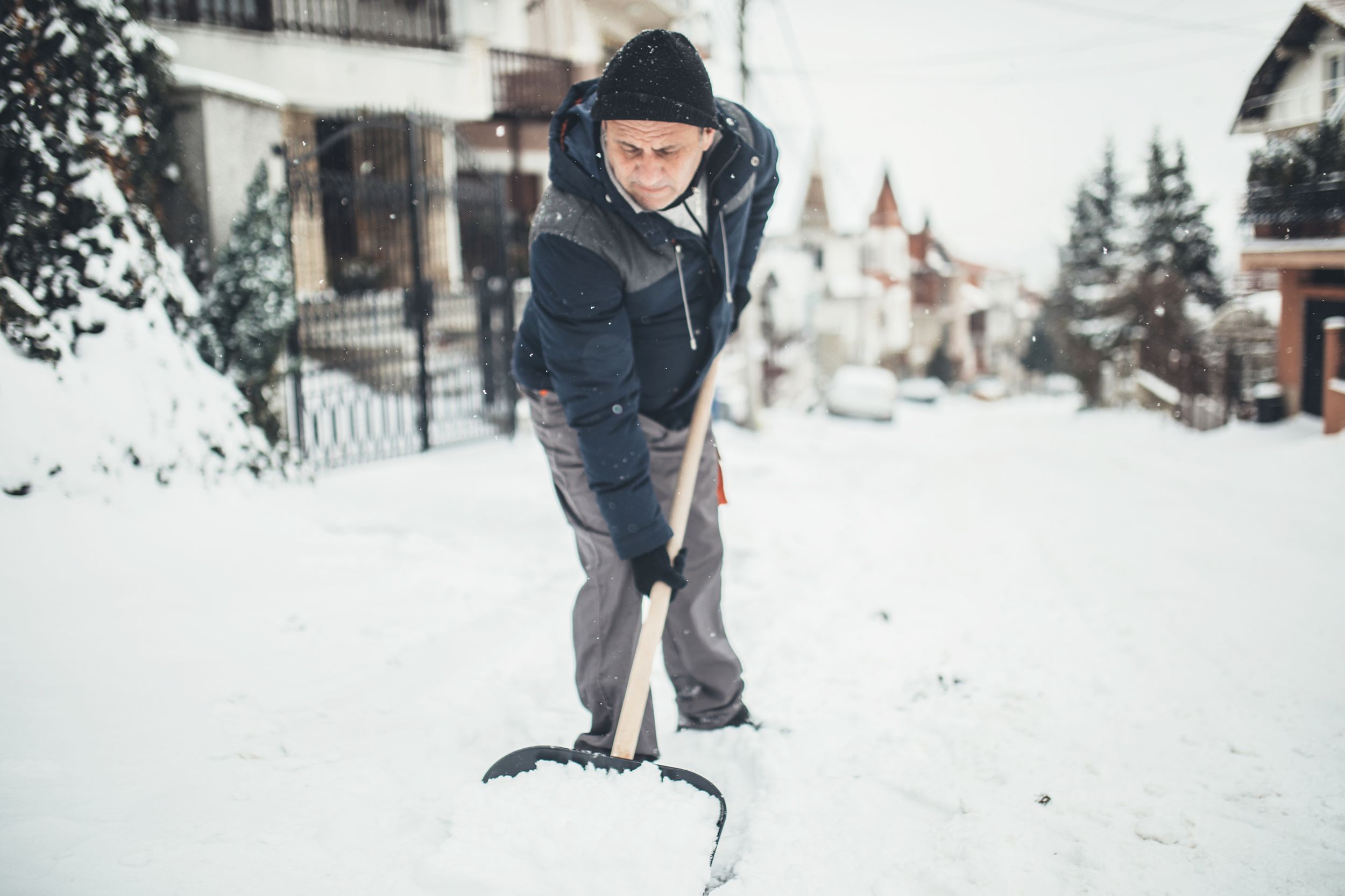 senior man cleans sidewalk in winter