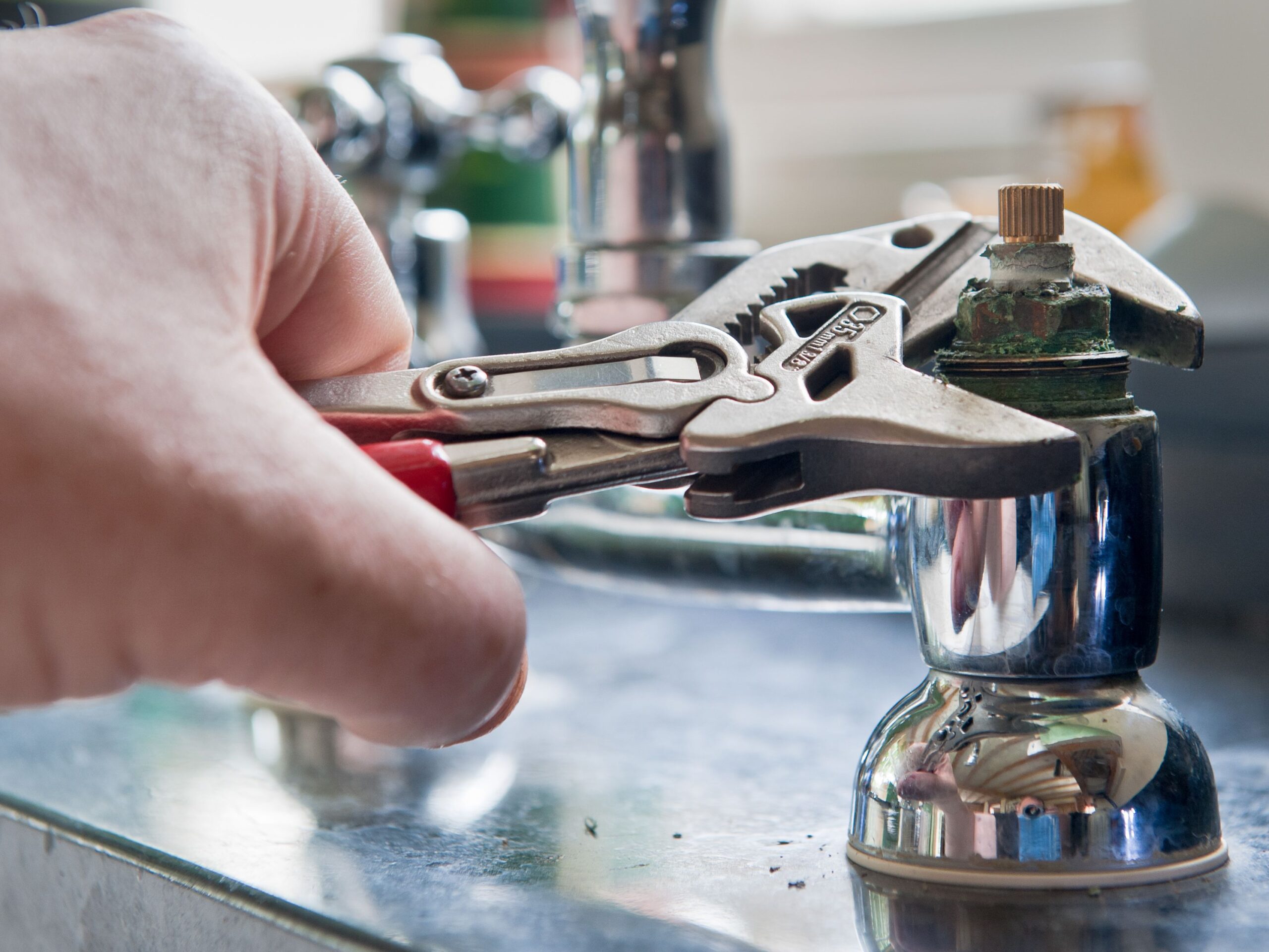 Real life situation-A plumber uses adjustable grips to remove a worn insert from a set of kitchen taps with a view to replace the damaged part.