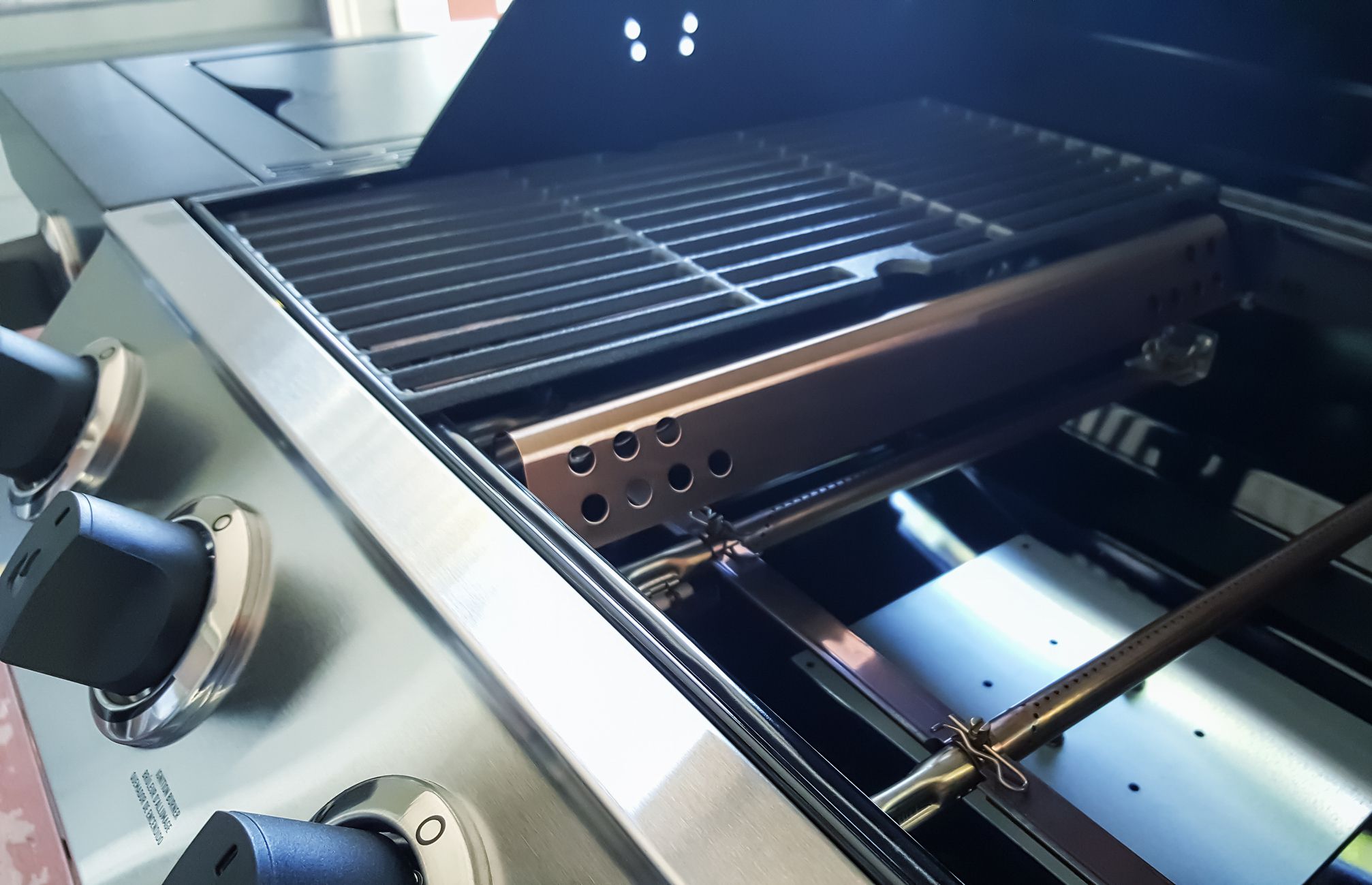 Closeup of Gas Barbecue Grill burners, flavorizer bars, porcelanized cast iron grids, and control knobs