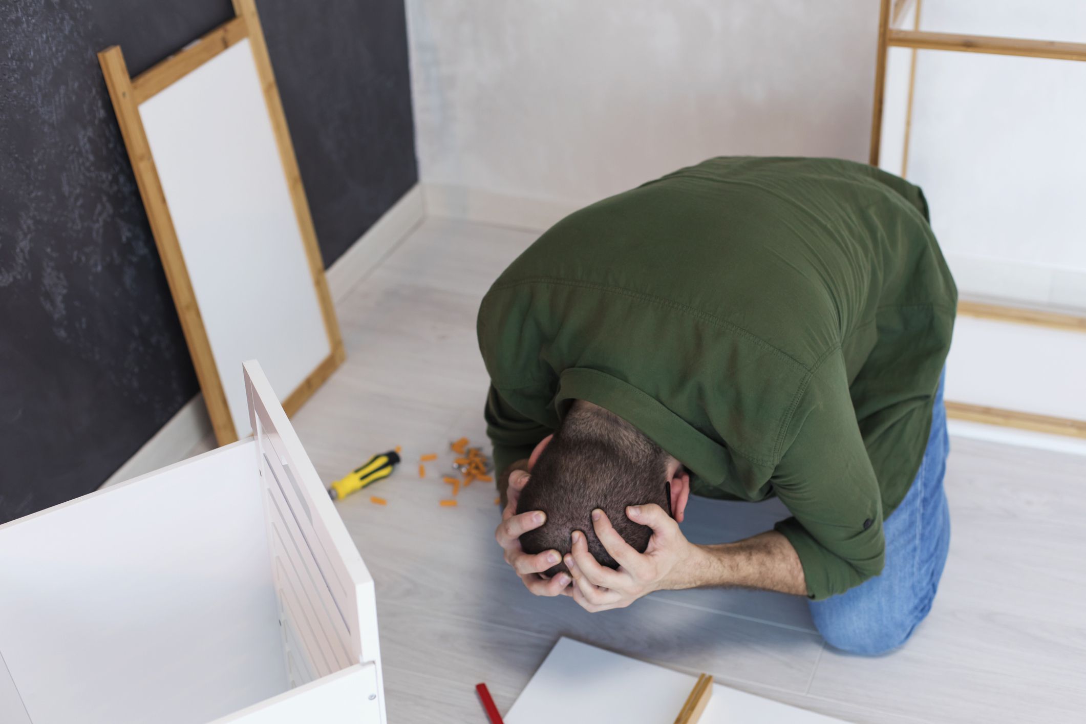 a young man frustrated with the instruction manual trying to assemble furniture