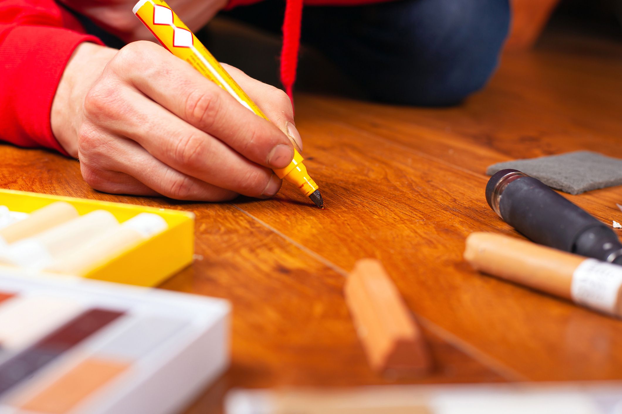 repair restoration laminate flooring parquet and wood products.sealing scratches and chips. master processes the surface with a special pencil to remove scratches close-up.