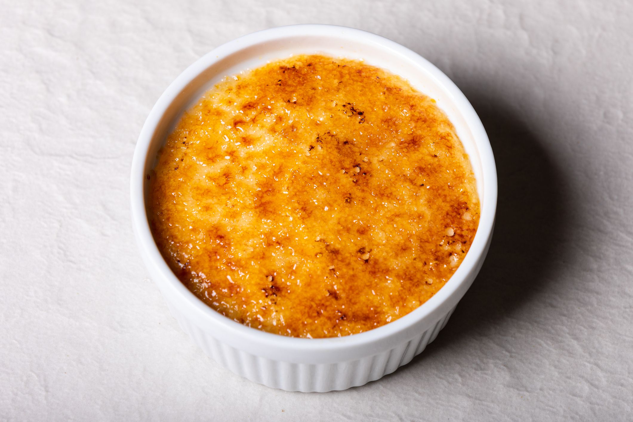 Fresh crème brulee in a small white bowl close-up on table