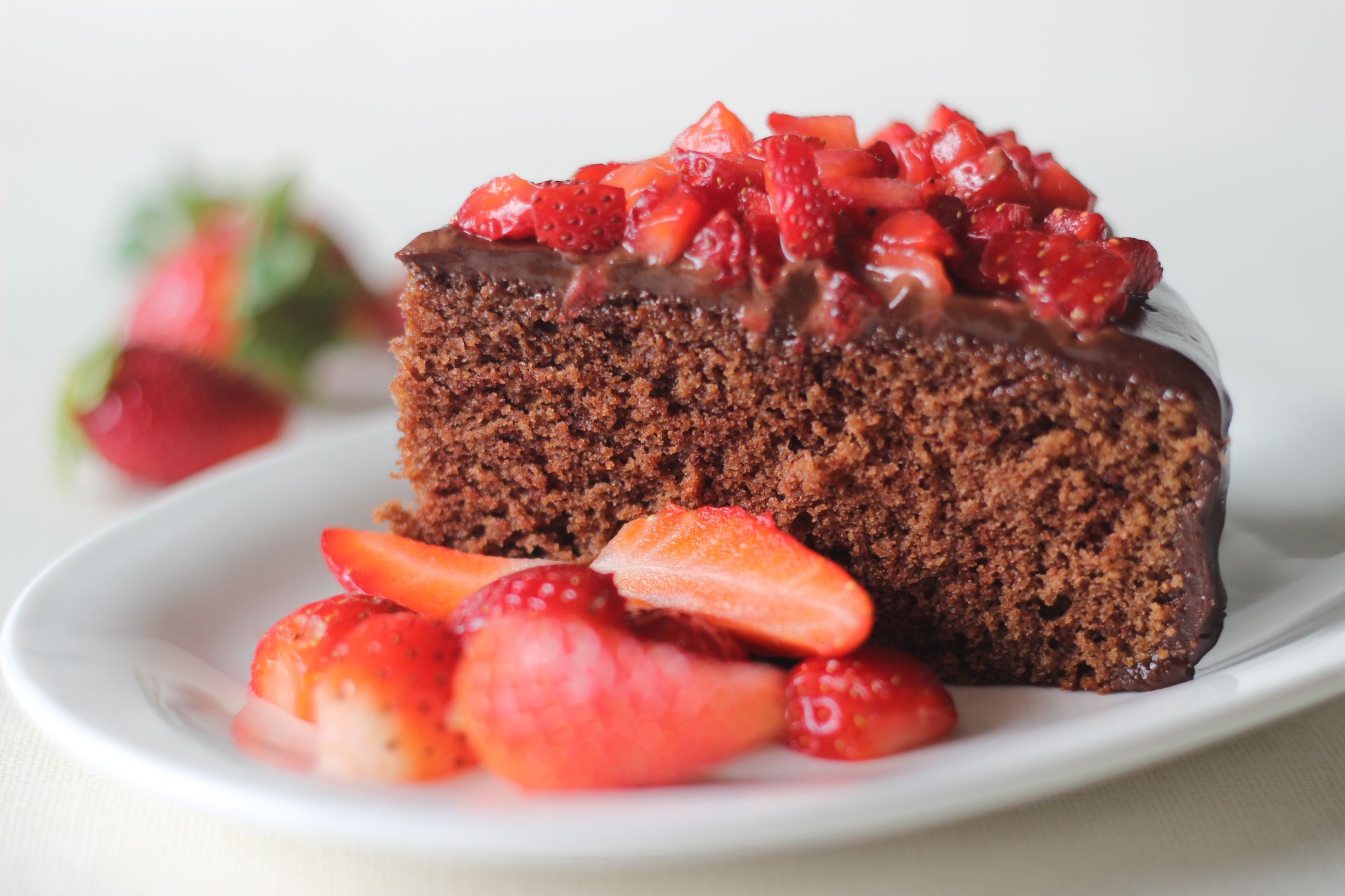 Chocolate cake slice with chocolate ganache and topped with fresh strawberries for a valentines day date and christmas day feast
