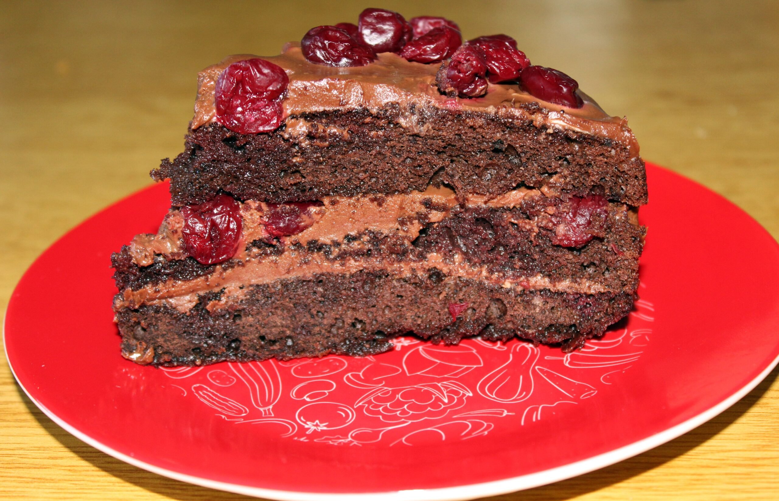 Black Forest (or Foret Noir) cake with brown cream and sour cherries on a red plate