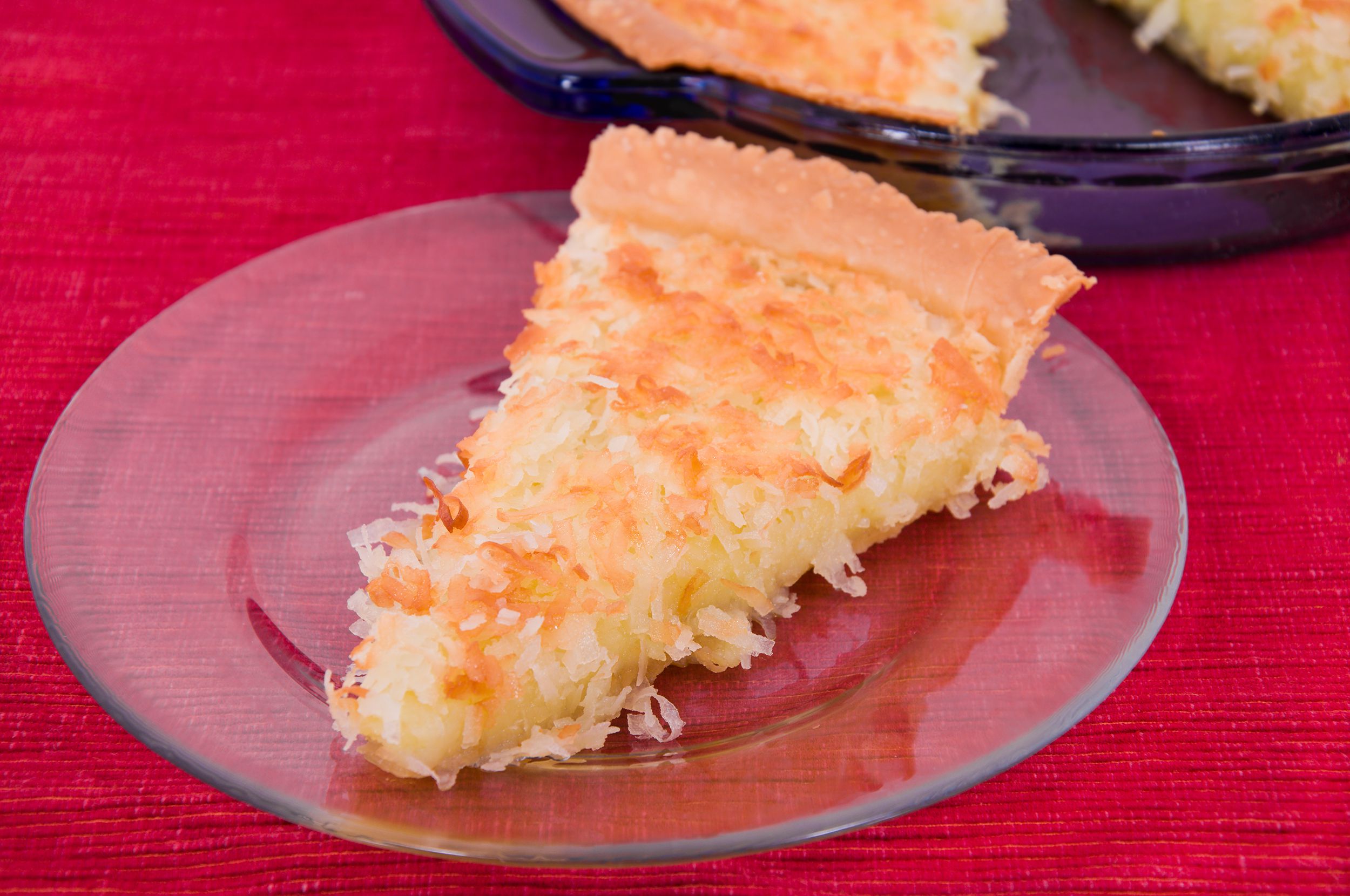 A single slice of coconut pie seperated from the rest of the pie in the background.