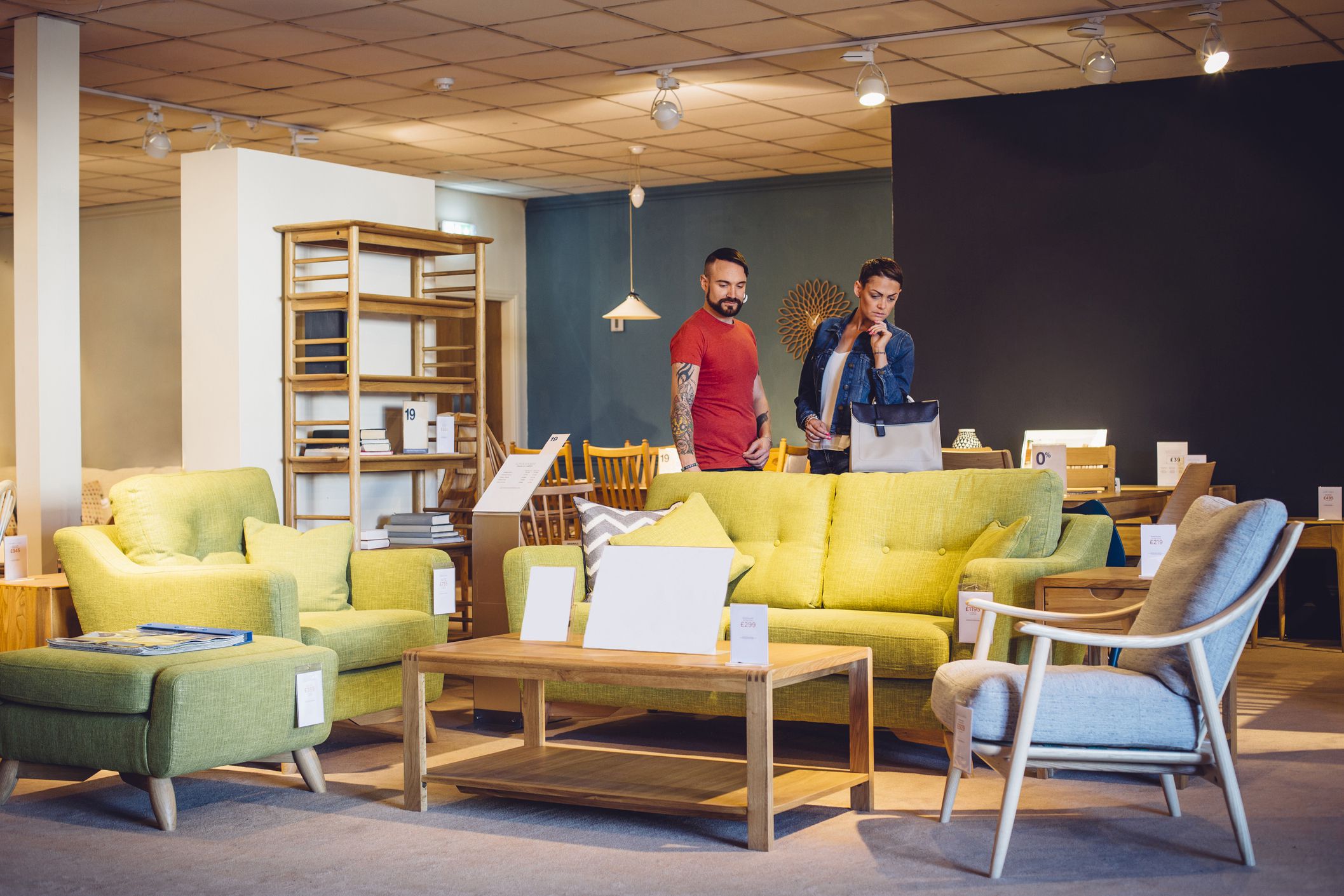A middle aged couple are shopping in a furniture store for items for their new home. they are both browsing the living room items and look thoughtful.
