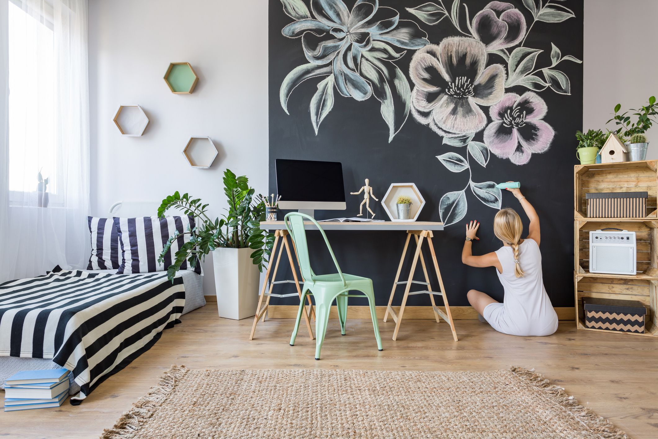Woman drawing flowers on chalkboard wall in multifunctional home interior