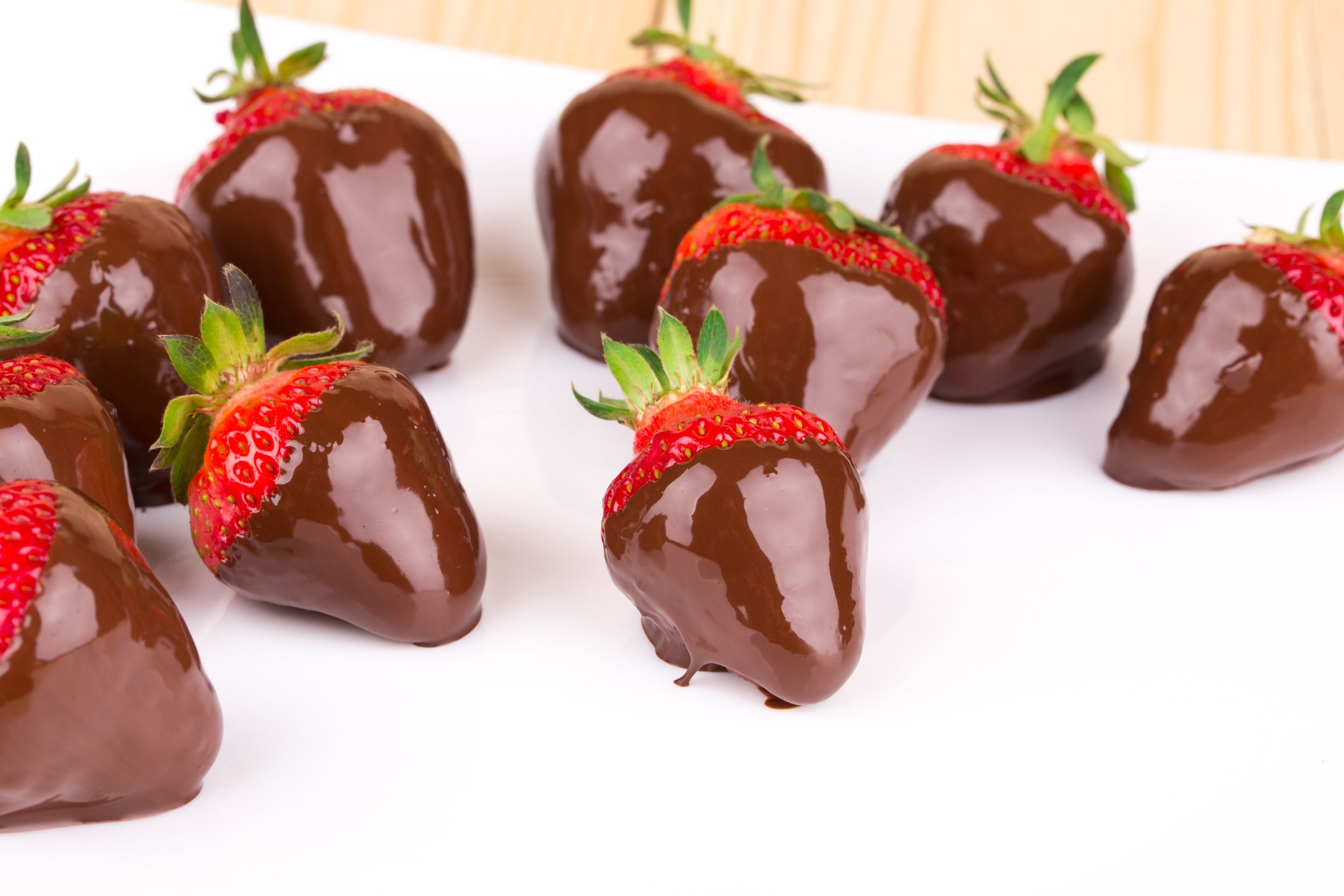 Gourmet Chocolate Covered Strawberries on the white plate. Wooden background.