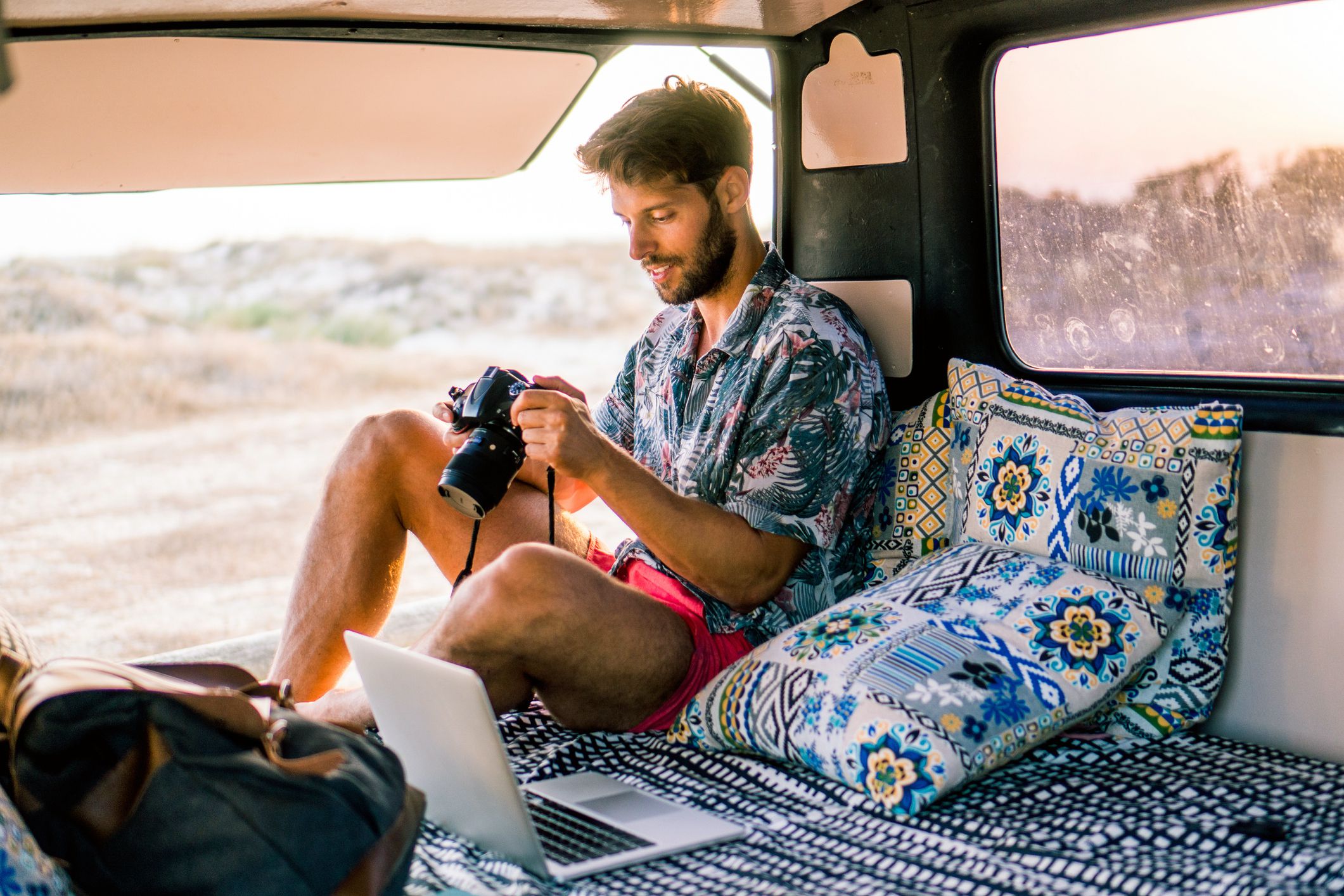 man in van looking at camera, laptop beside him