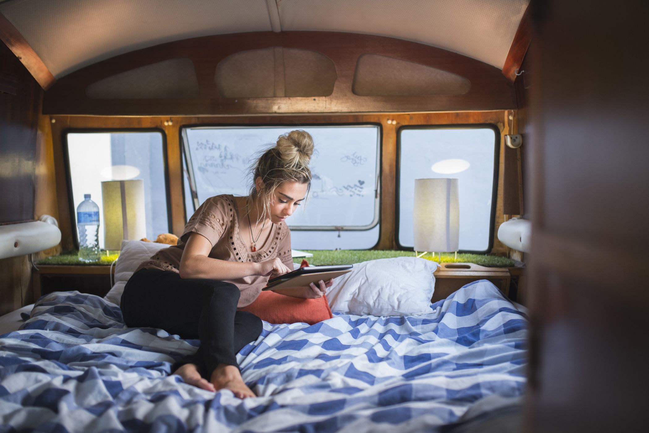 young woman in camper van trying to connect to internet on tablet