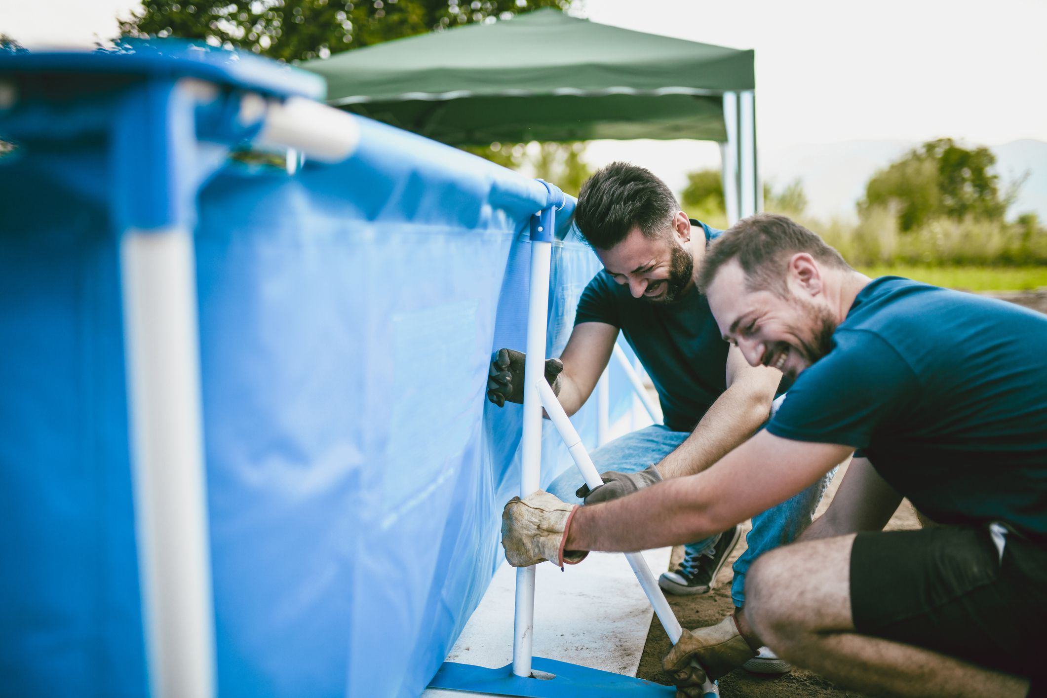 Handsome Male Workers Having Trouble Setting Up Pool
