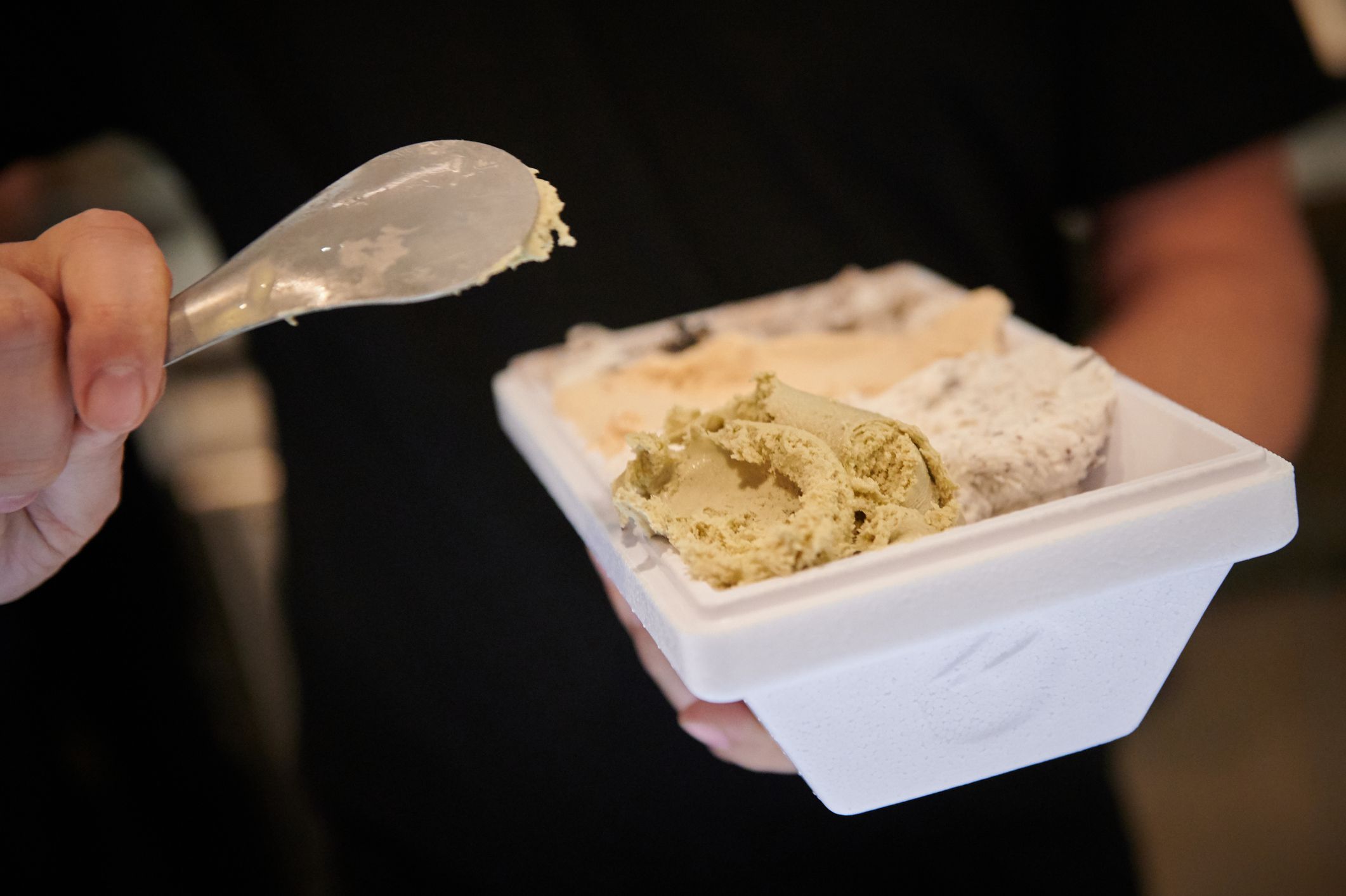 Man holding a take out box filled with 4 flavors ice cream