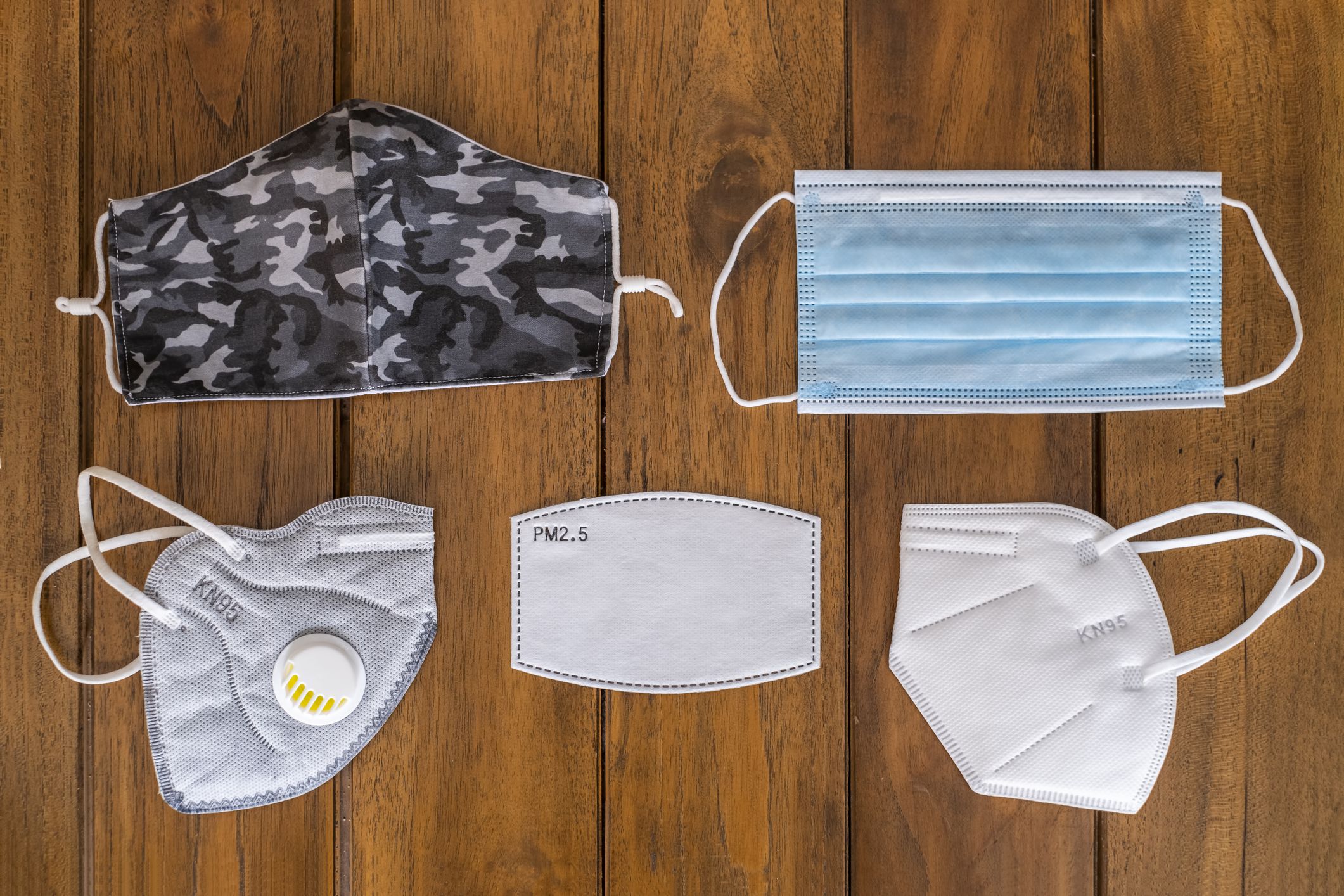 different kinds of face masks for protection against COVID-19,FPP2, KN95, FP2.5 filter, hygienic mask, surgical mask, and textile reusable face mask, on a wooden background top view
