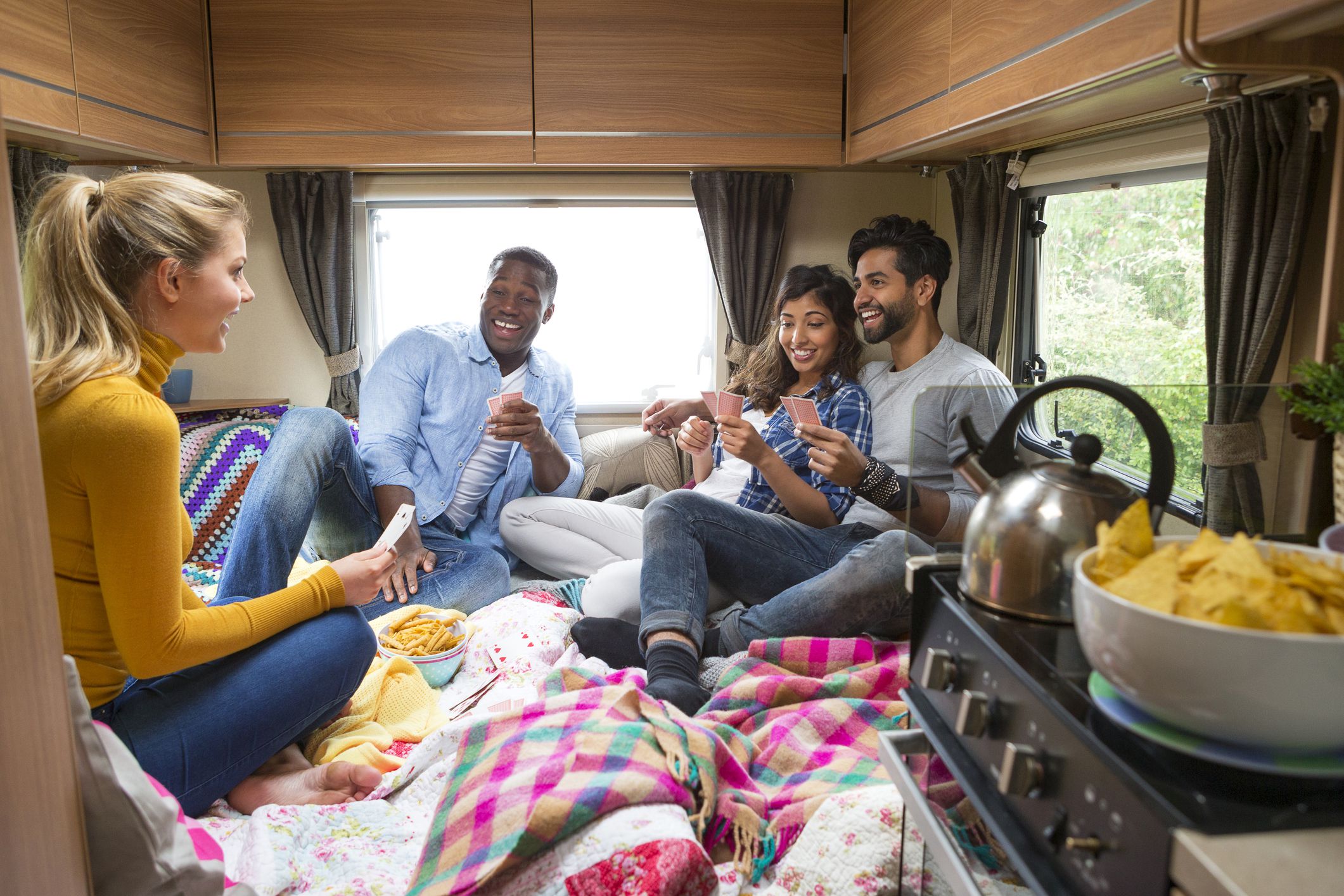 group of young people talking and playing cards in camper van