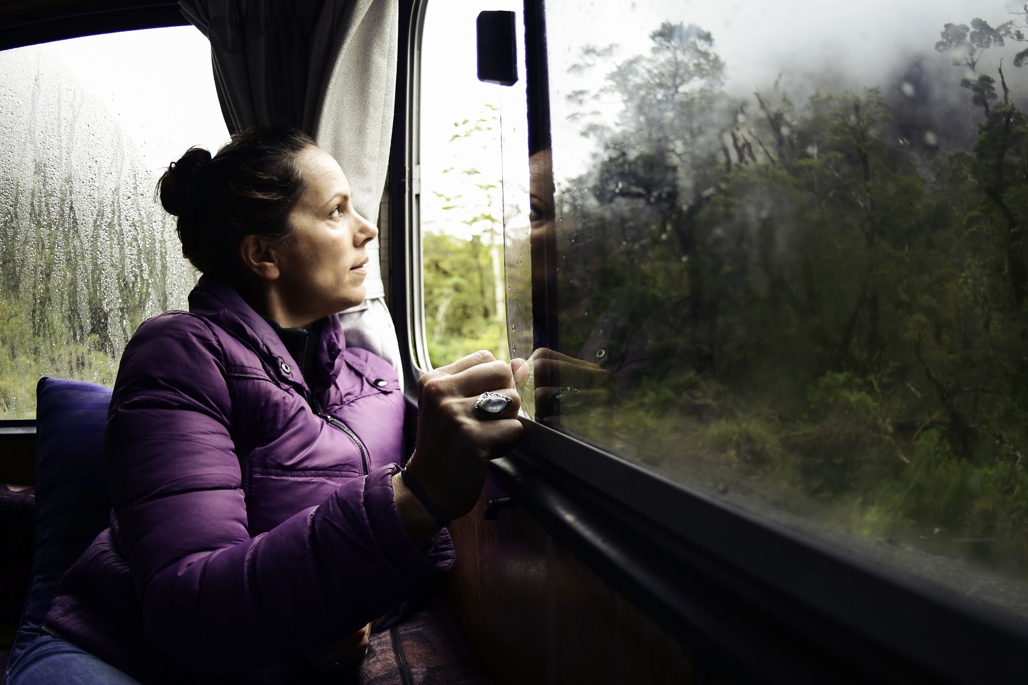 woman in camper van looking out window at rain