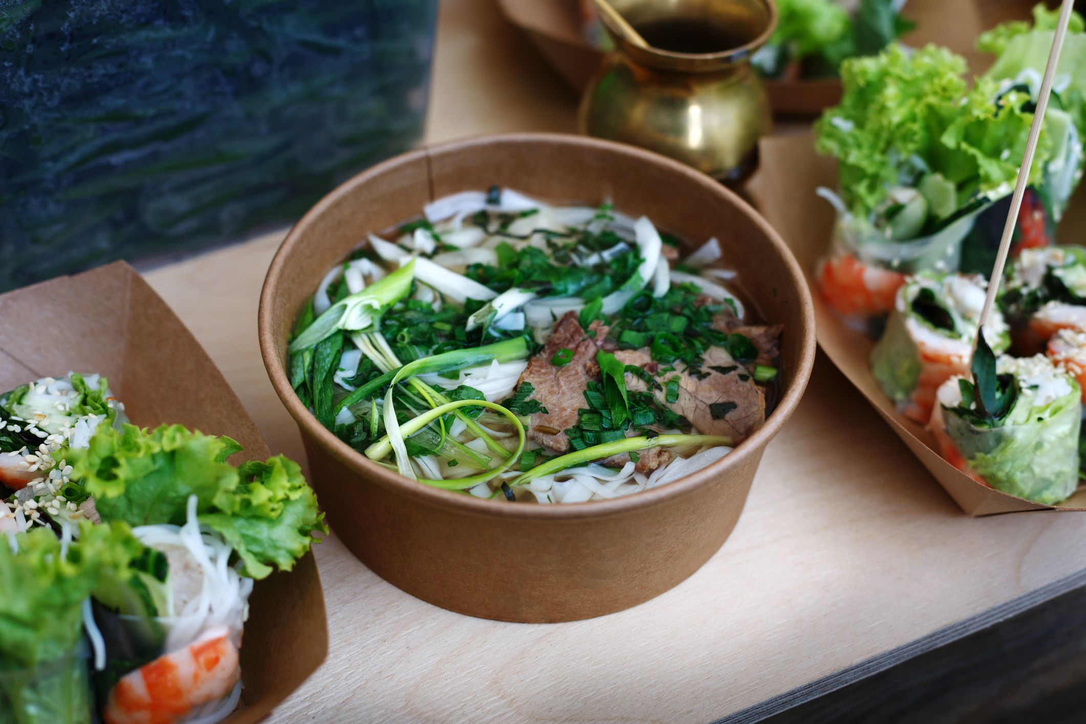 Thai take away street food, tom yam kung soup. Traditional hot spicy curry soup with meat, greenery and noodles, outdoor fast food market