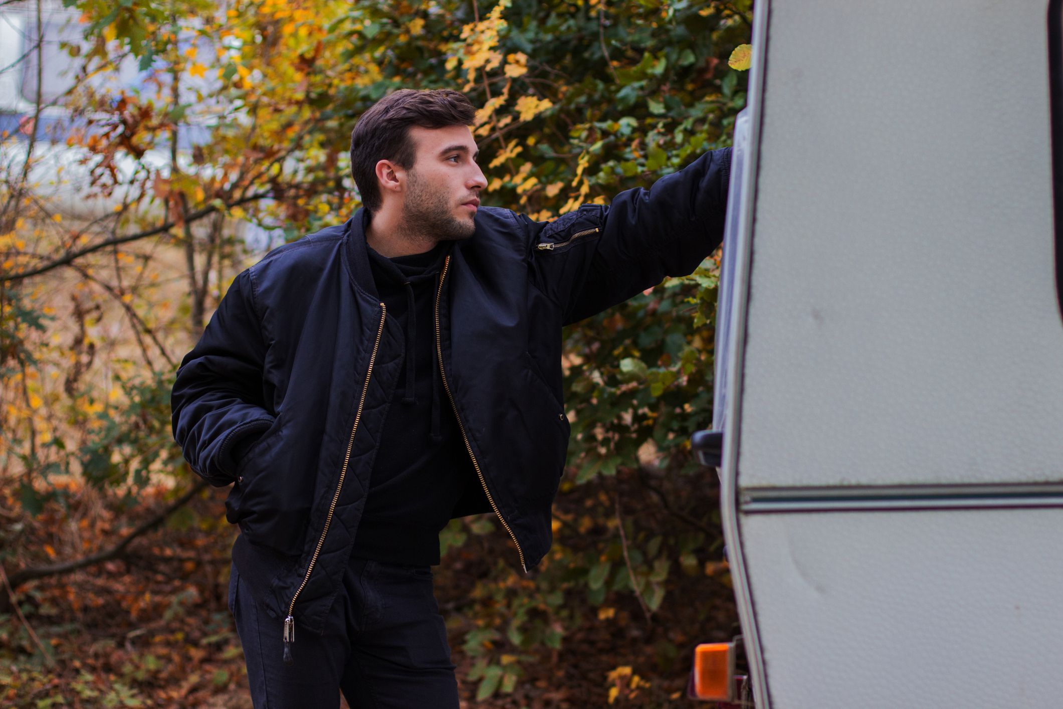tired and sad-looking man leaning on camper van